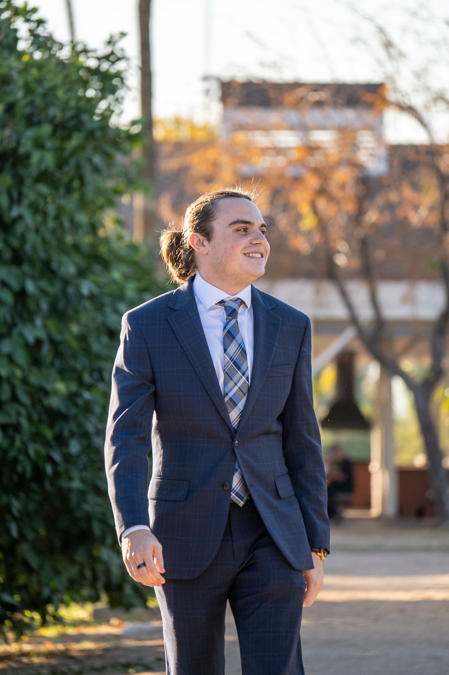 A man in a suit is walking outside and smiling.