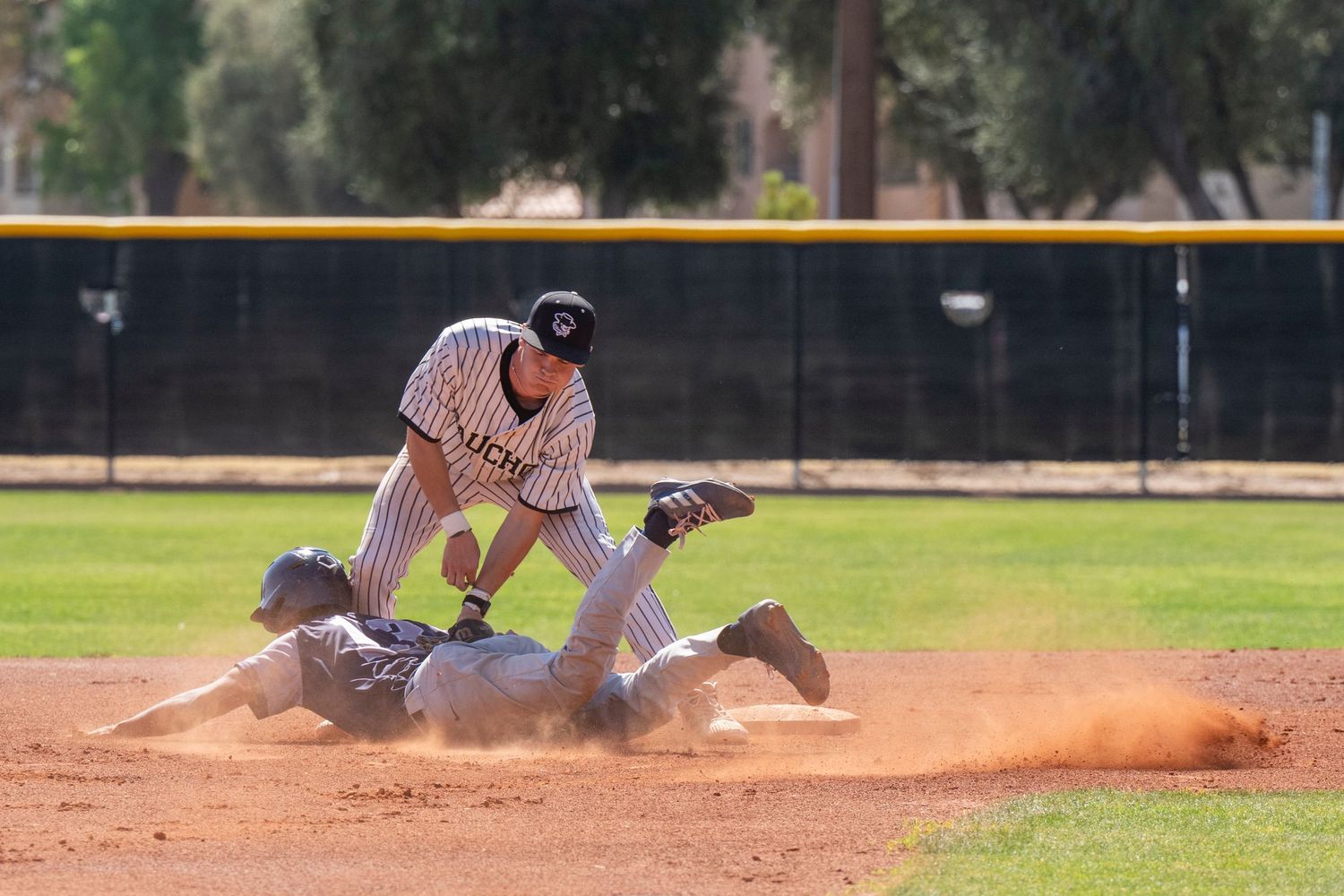 Baseball player who has caught a ball and another player who dove for the base.