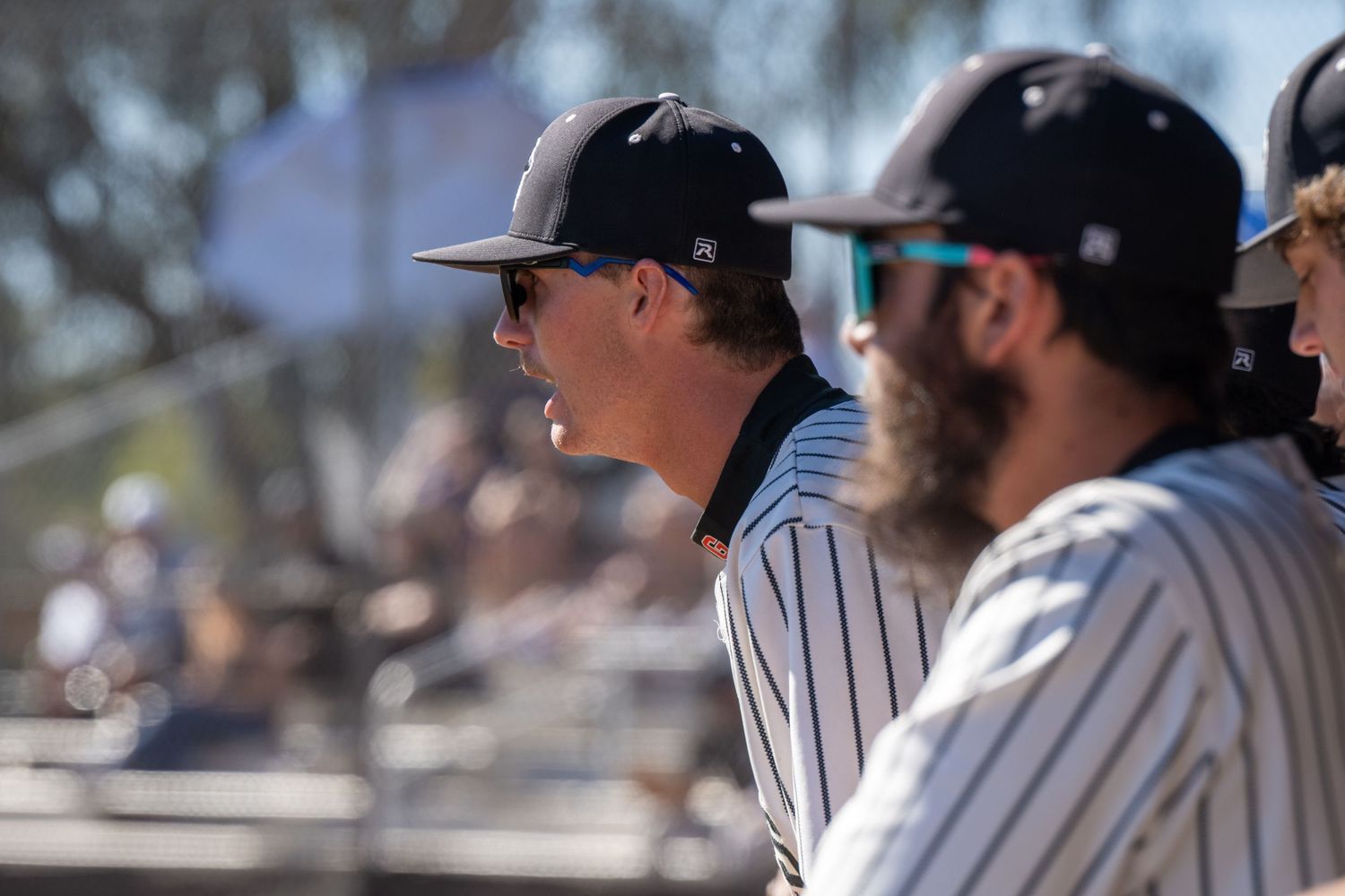 A baseball player in the dugout who is leaning over the fence and shouting.