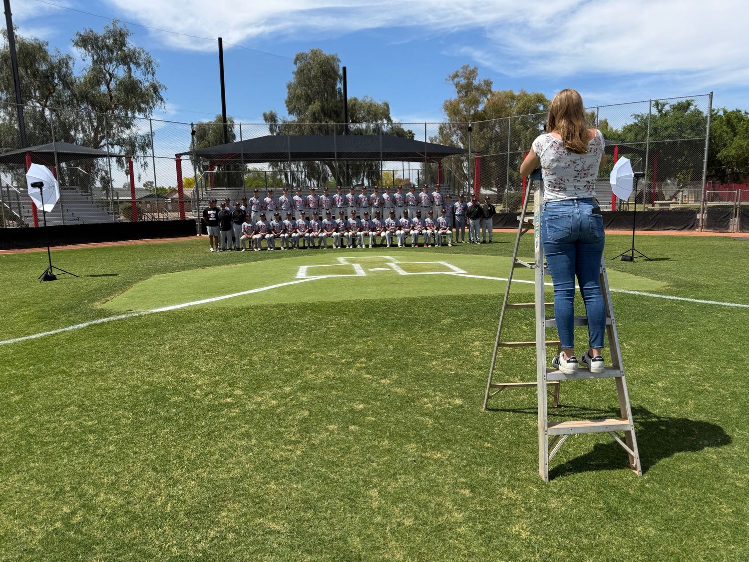 Danielle Gantt standing on a ladder taking a team photo of the GCC Baseball team.