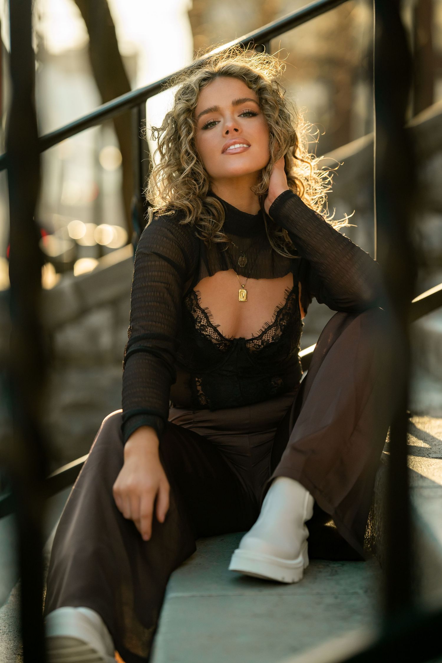 Fashion portrait in black mesh top with backlighting creating a golden glow effect.