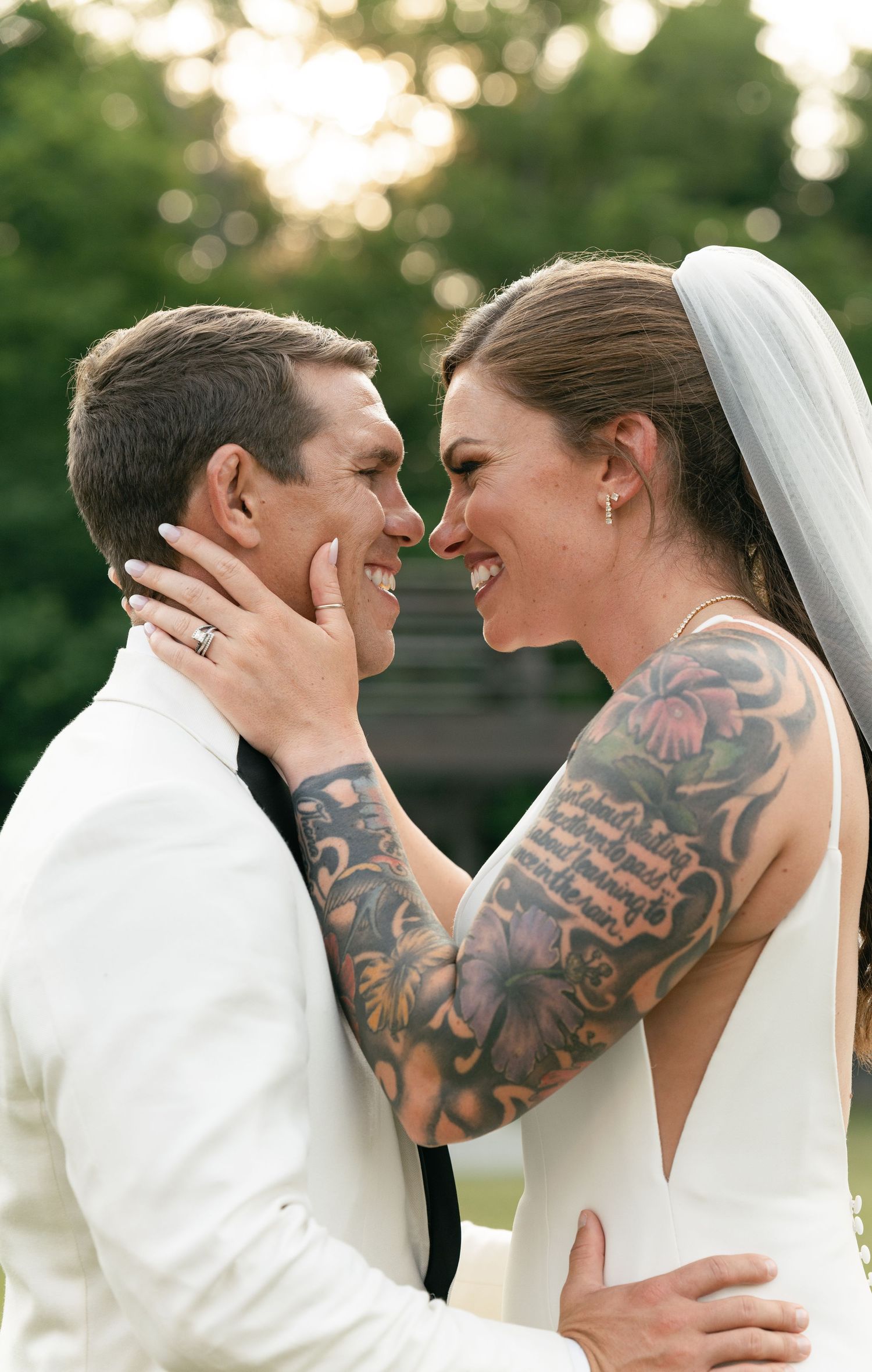 A tender wedding moment between newlyweds sharing an intimate embrace outdoors at sunset.