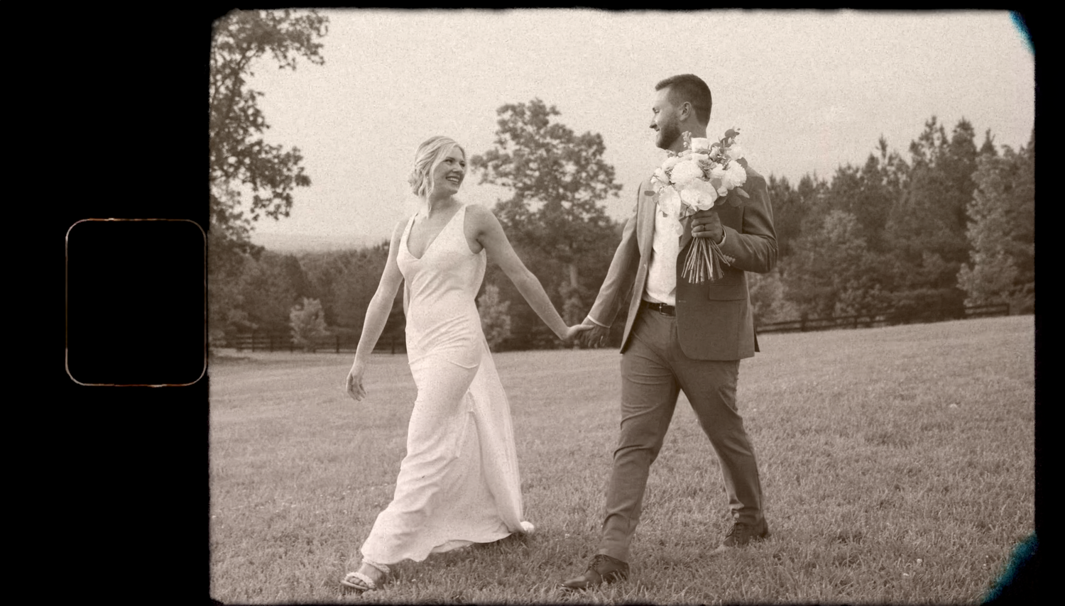 A vintage-style black and white photo of a couple dancing joyfully in a field.