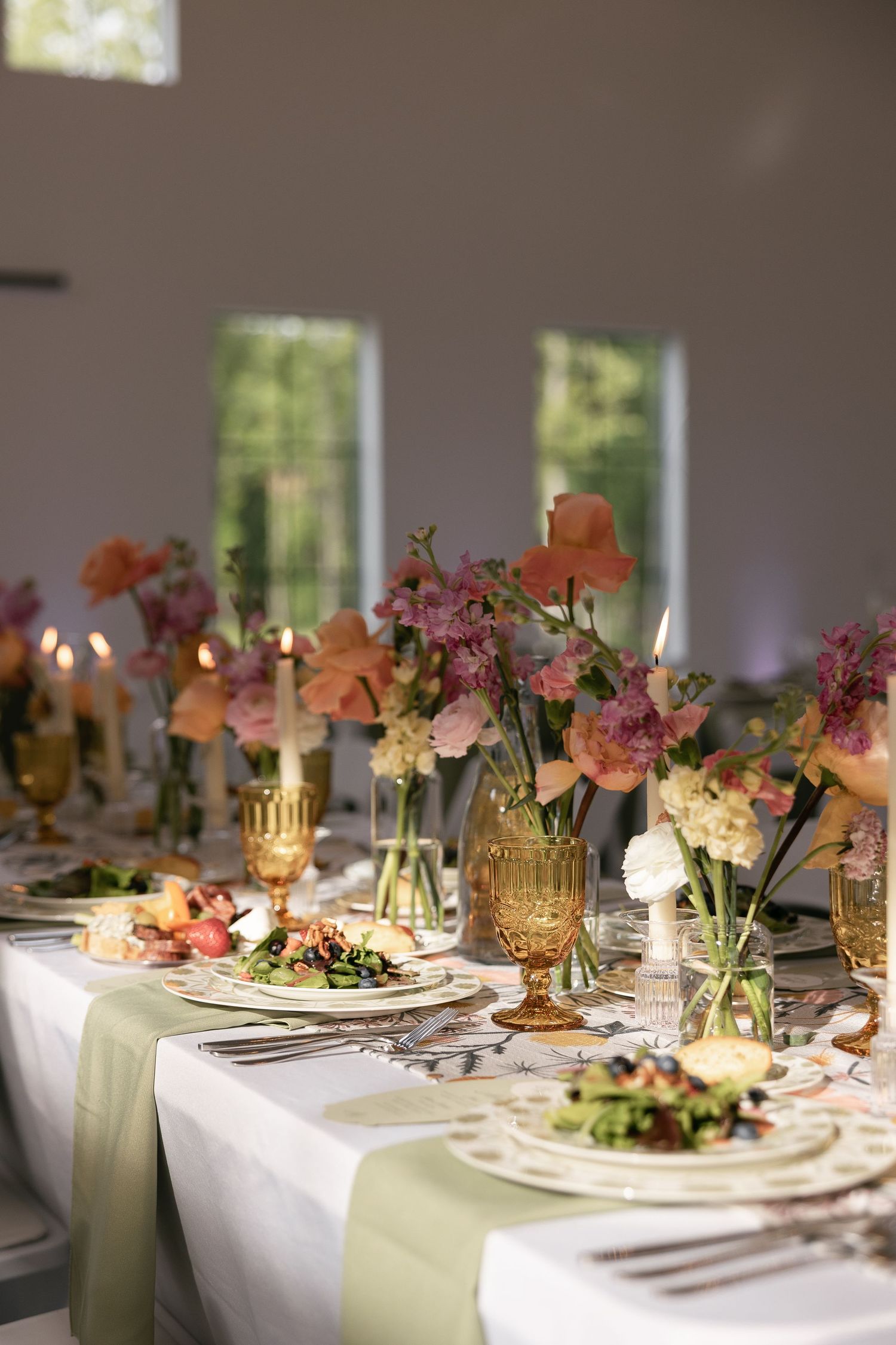 Elegant wedding reception tables decorated with pink and peach floral centerpieces, gold candleholders and white linens.