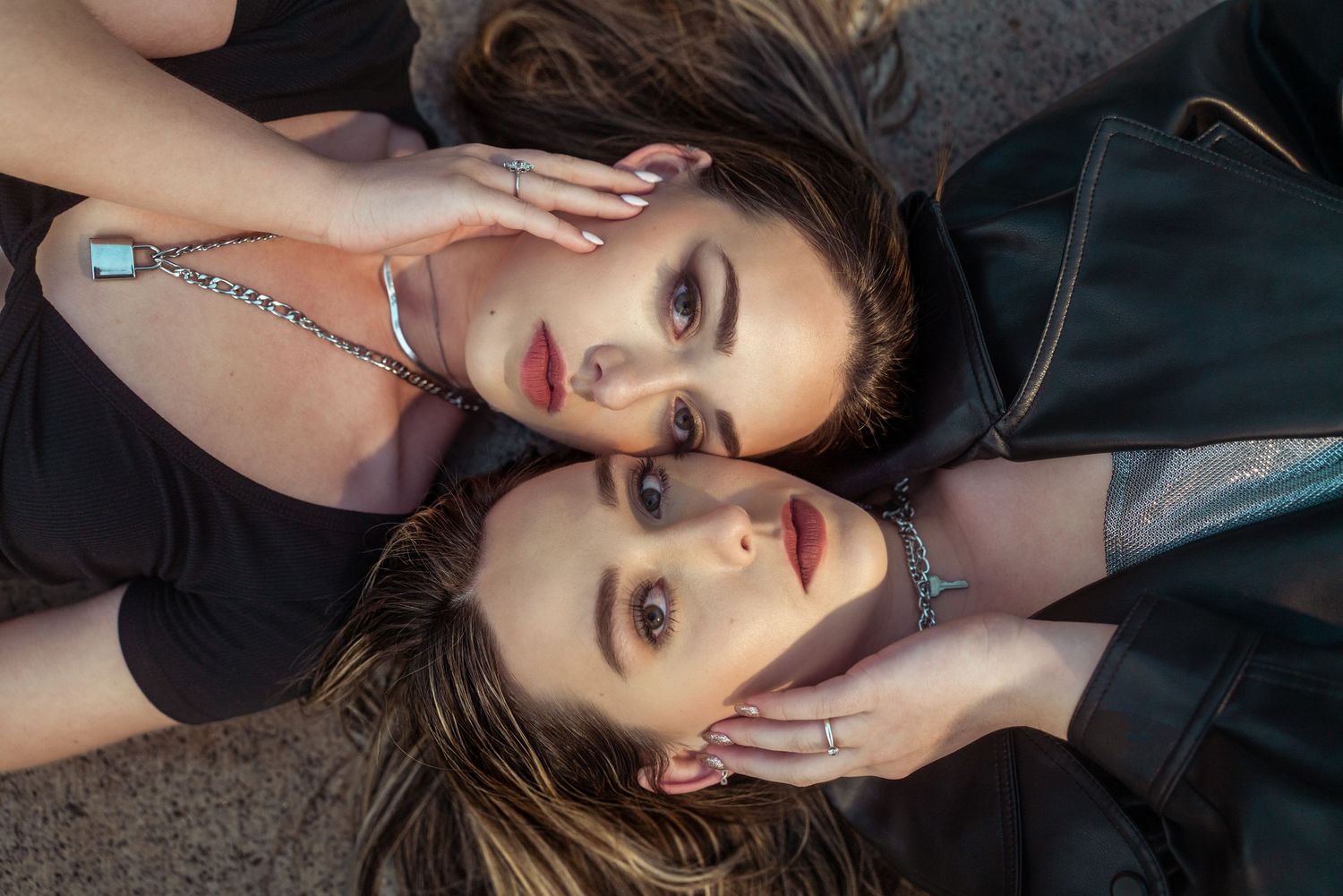 Two friends lying head to head in dark clothing for artistic portrait.