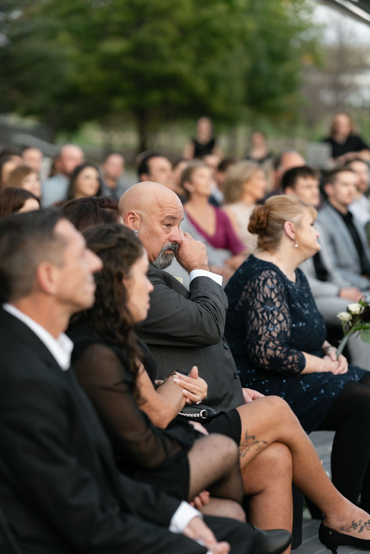 Wedding ceremony guests seated in formal attire showing emotional reactions.