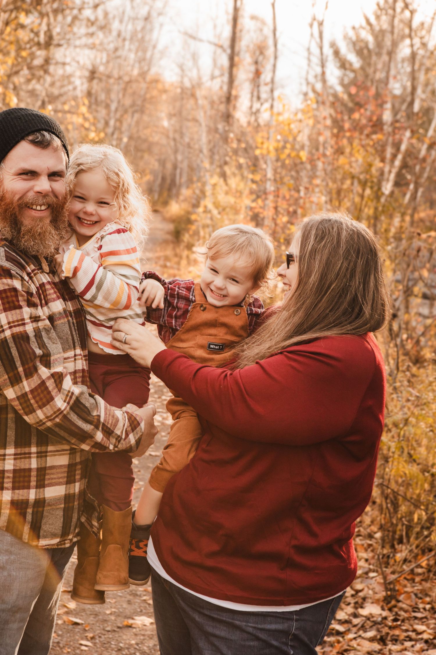 Family enjoying playful moments together on an autumn path surrounded by golden fall foliage.