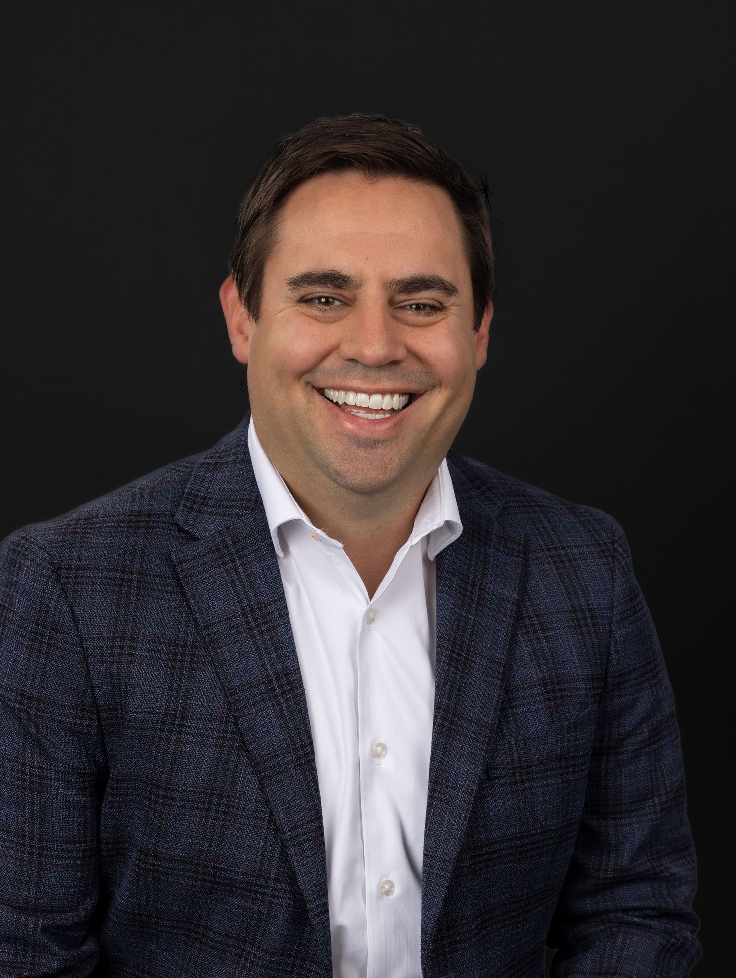 Professional headshot of CFO photographed in mobile studio setup with neutral textured background for website and LinkedIn.