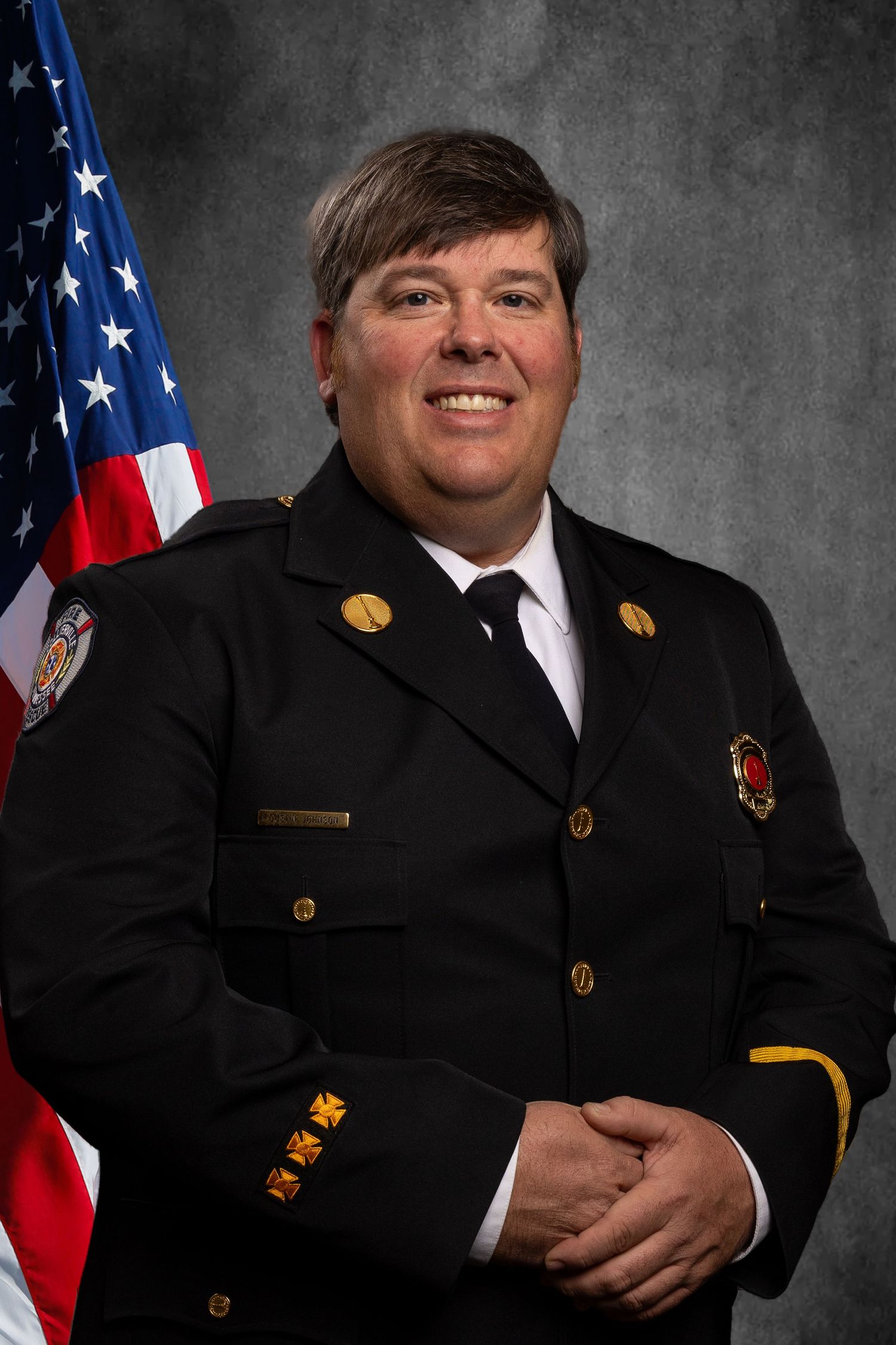 Headshot of member of non-profit, TN Professional Firefighters Assoc. on virtual background, smiling and in uniform.