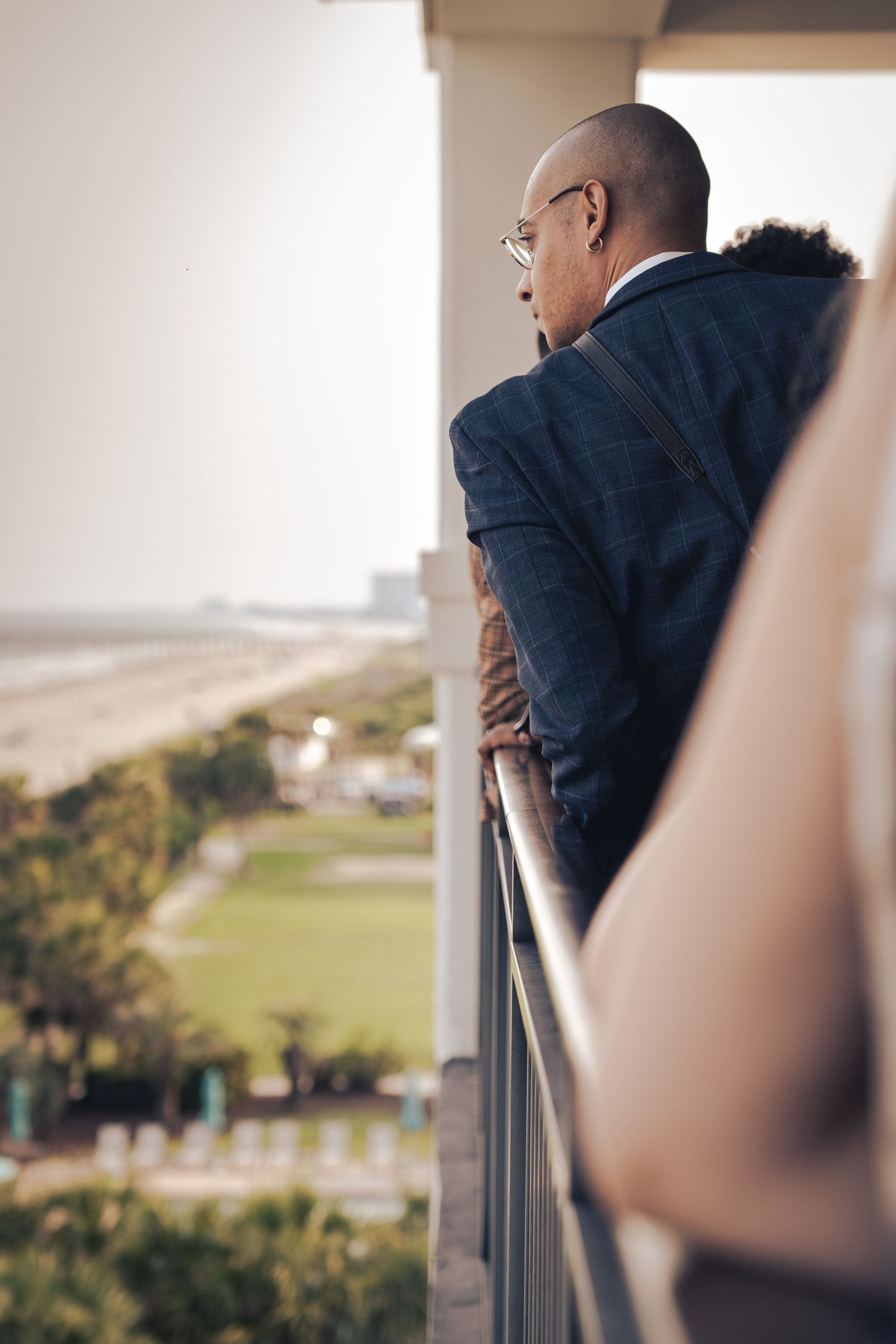 Male wearing a suit looking out over a balcony