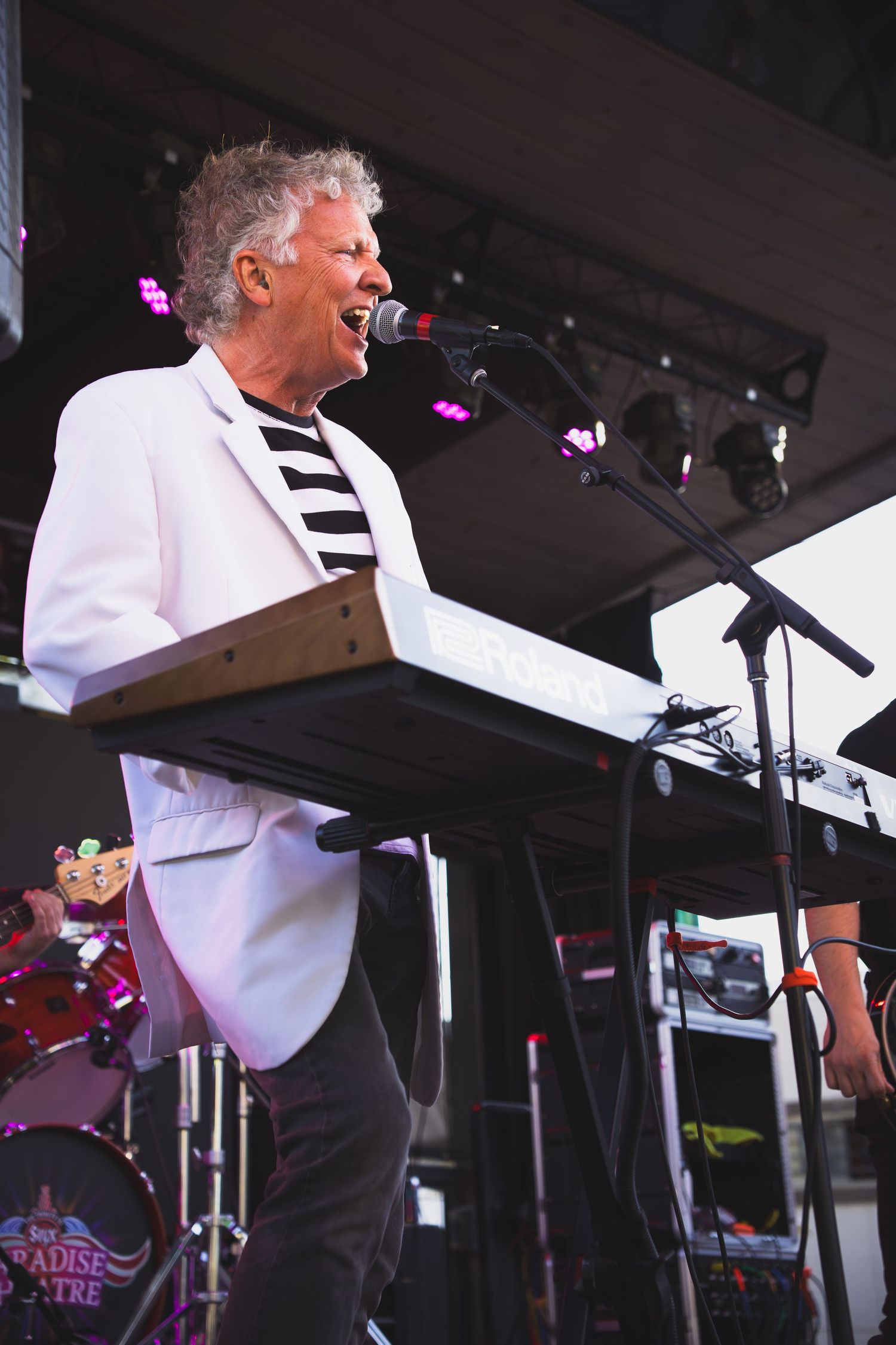 Male keyboard player on stage singing during performance