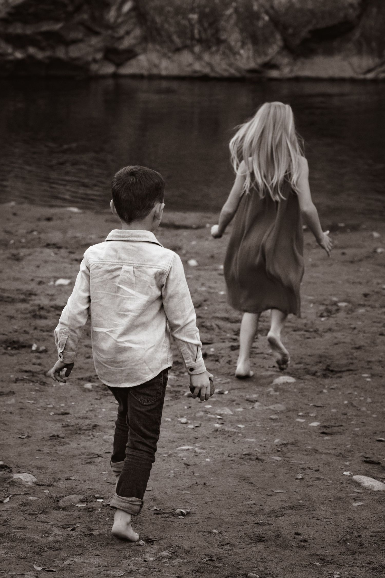 Black and white photo of children running towards the river, barefoot
