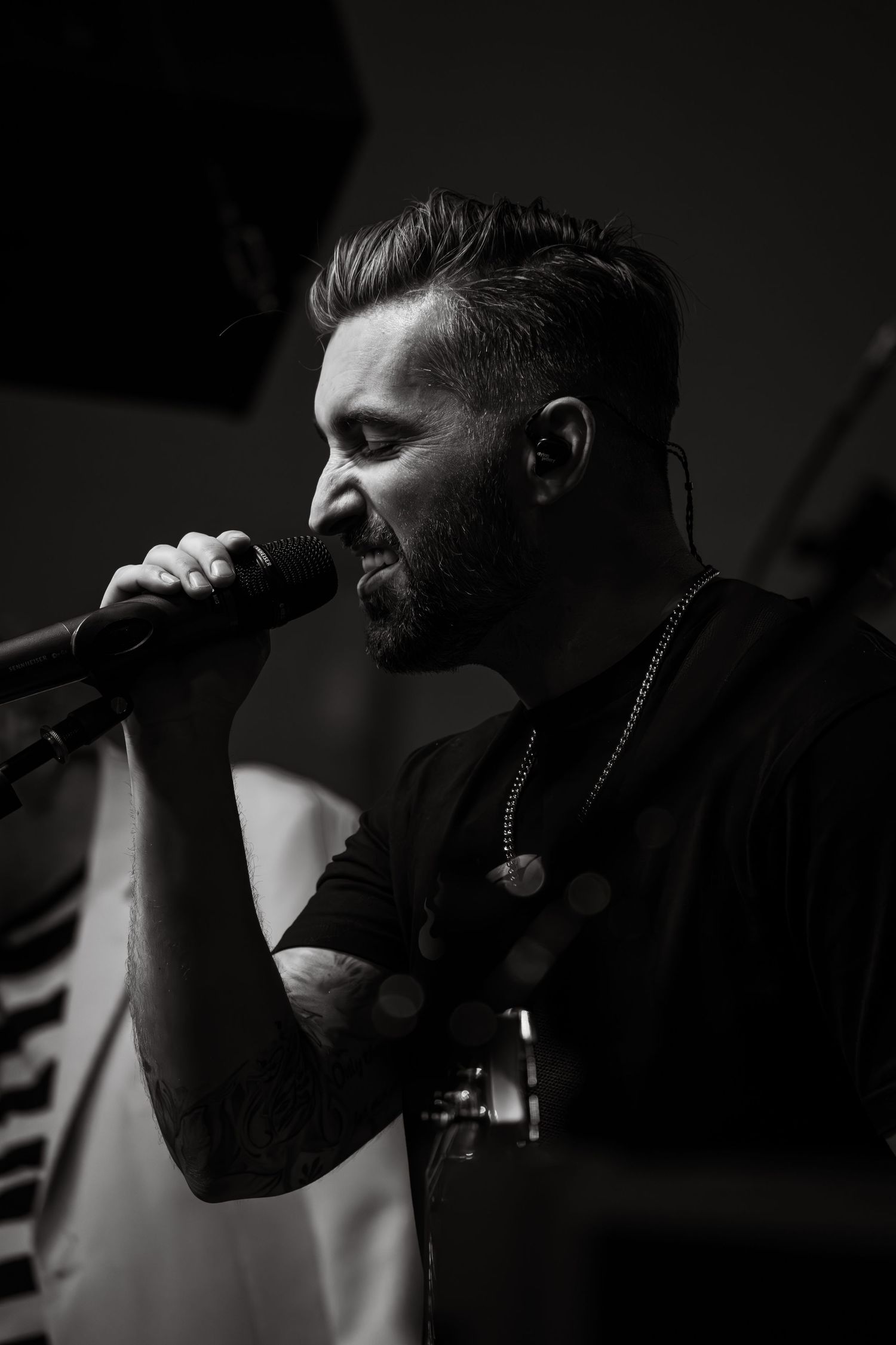 Black and white closeup of a man singing into a microphone on stage