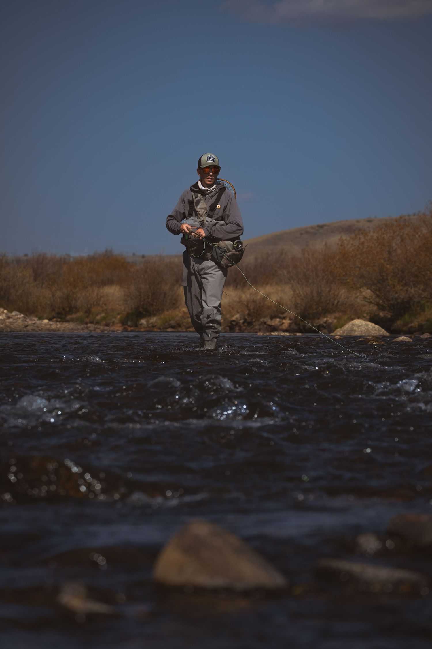 Man fly-fishing in river during sunny day in Colorado
