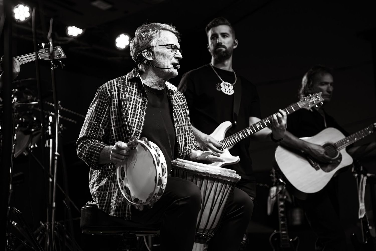 Black and white photo of a drummer and other band members performing on stage