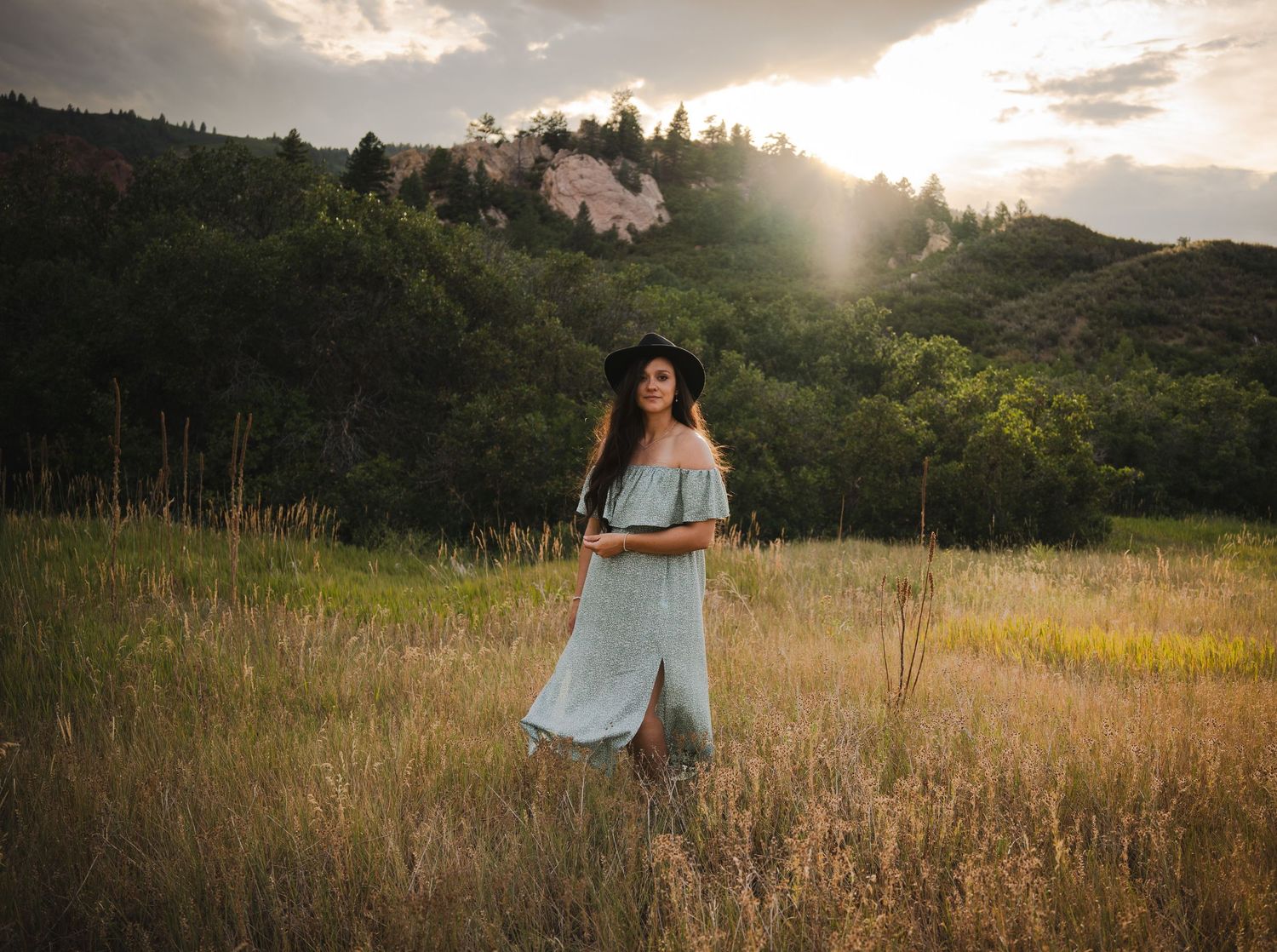 Woman in a dress standing in a field during sunset