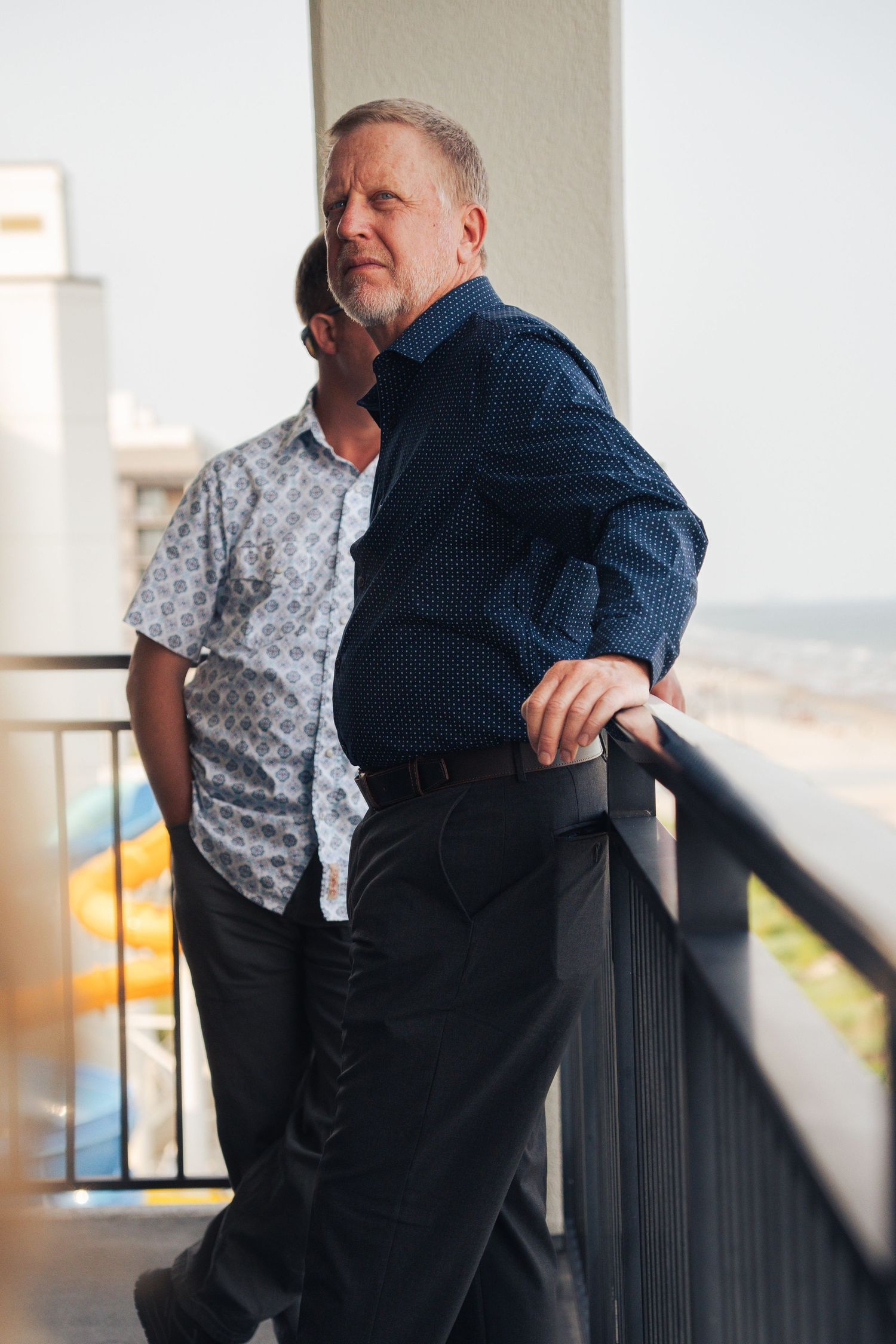 Man leaning against a railing in formal clothes
