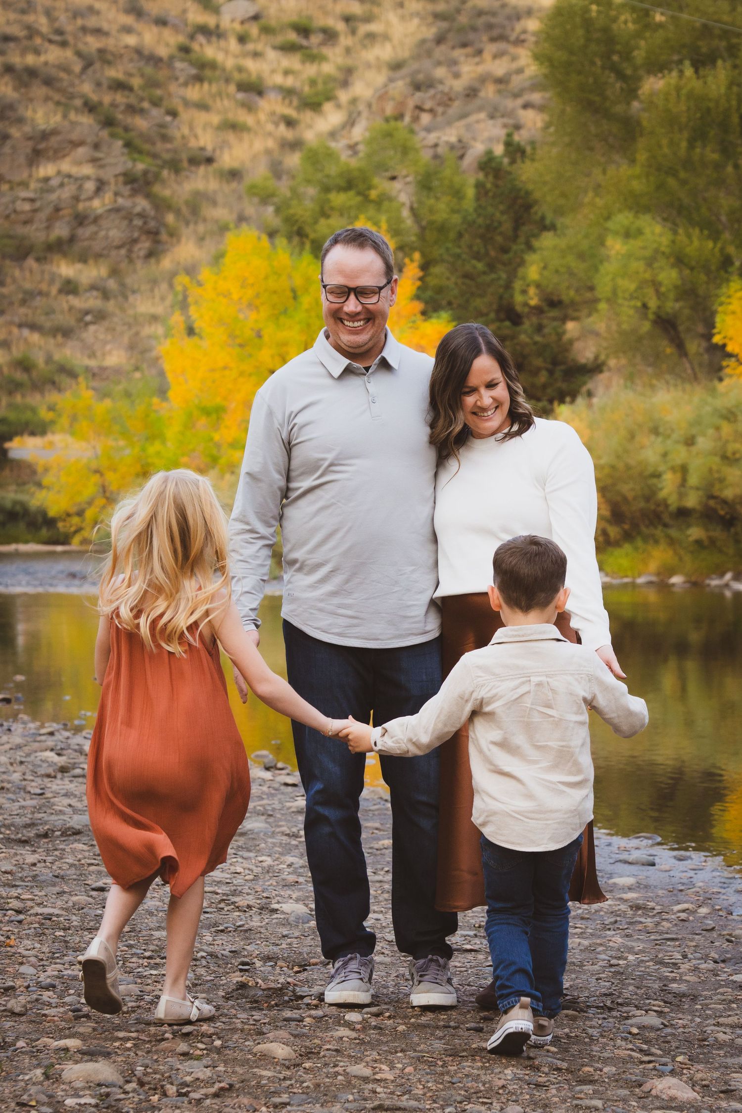 Kids running towards their parents by the river during the fall