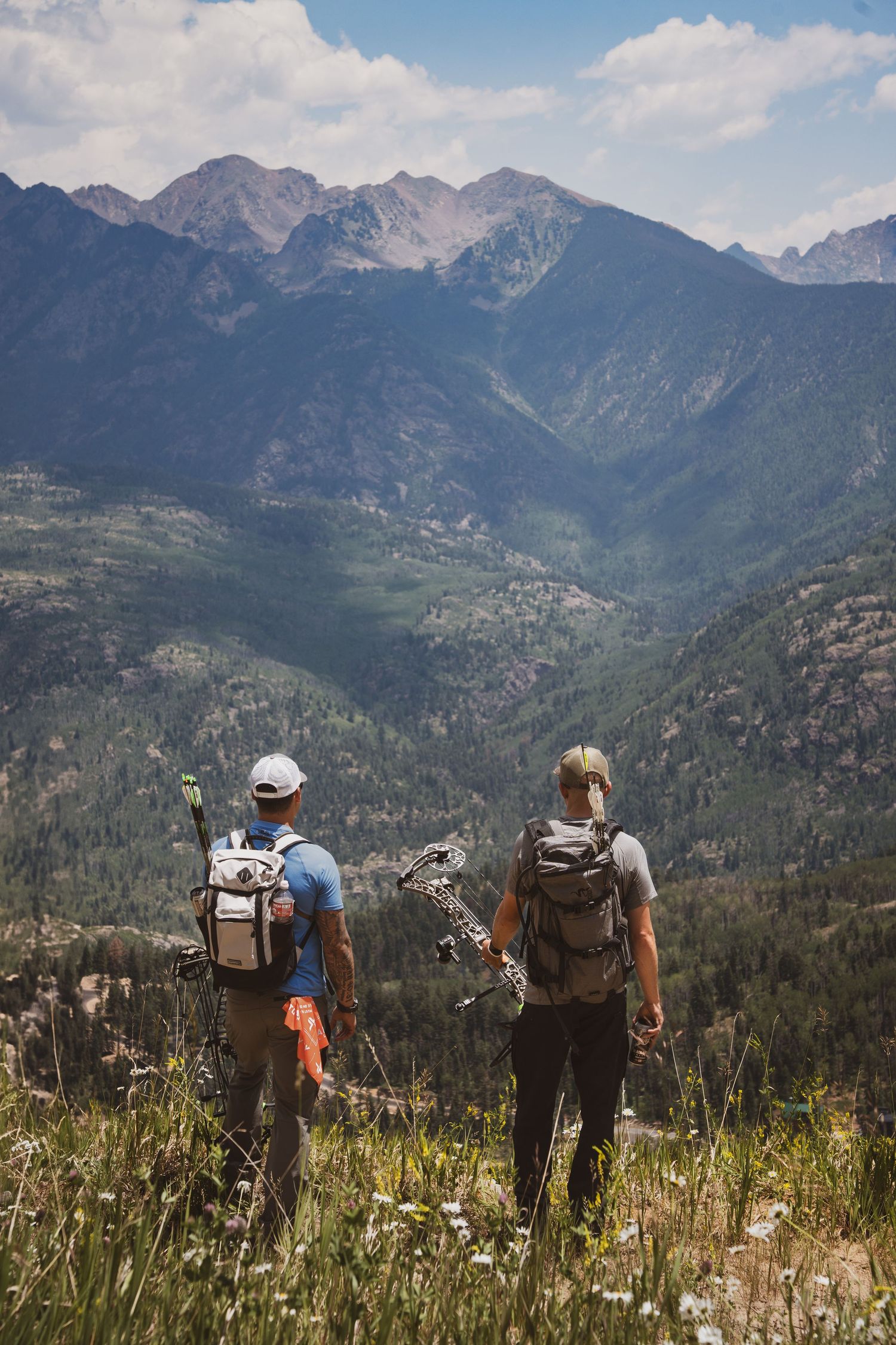 Two men looking out over a mountain range with bows and arrows