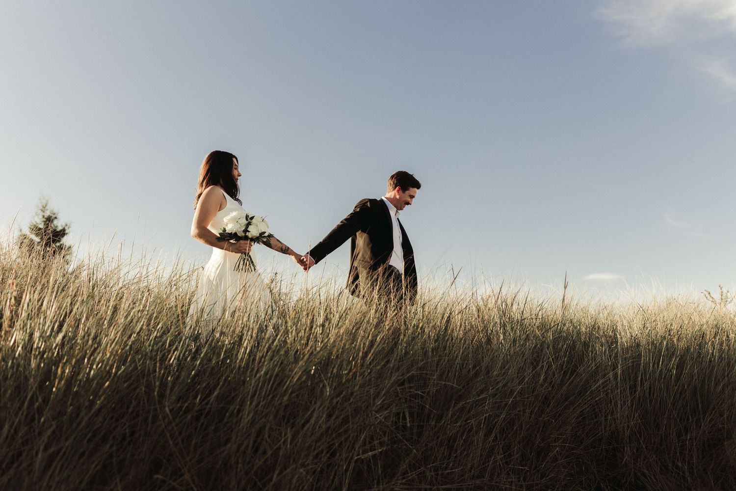 A couple stand together in a golden field during sunset creating a romantic outdoor scene.