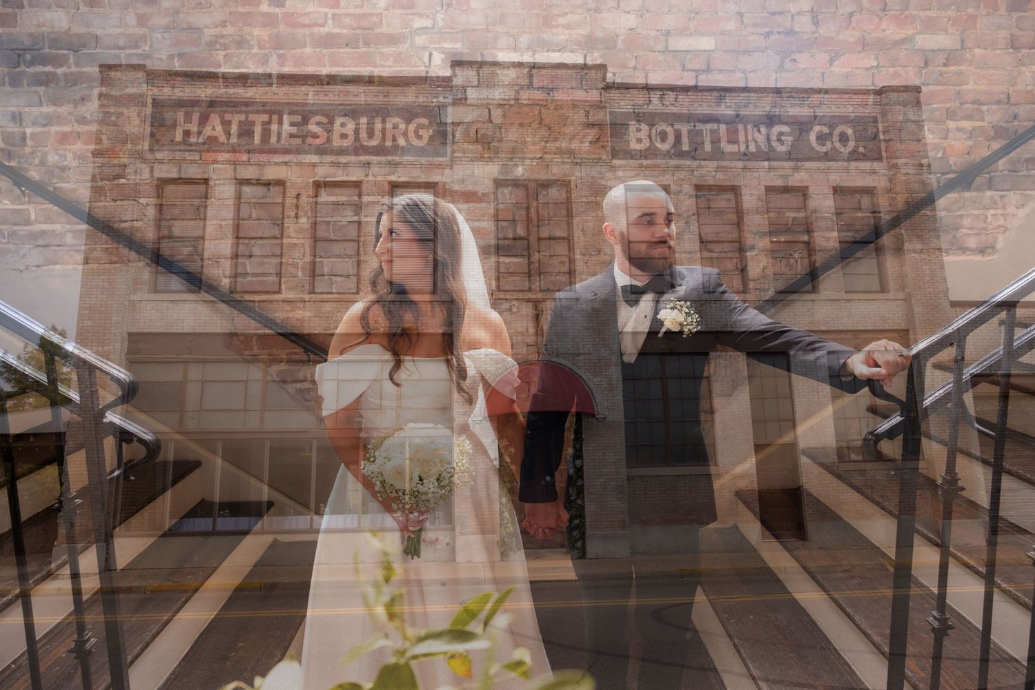 Creative double exposure wedding photo of bride and groom reflected in glass outside Hattiesburg Bottling Co.