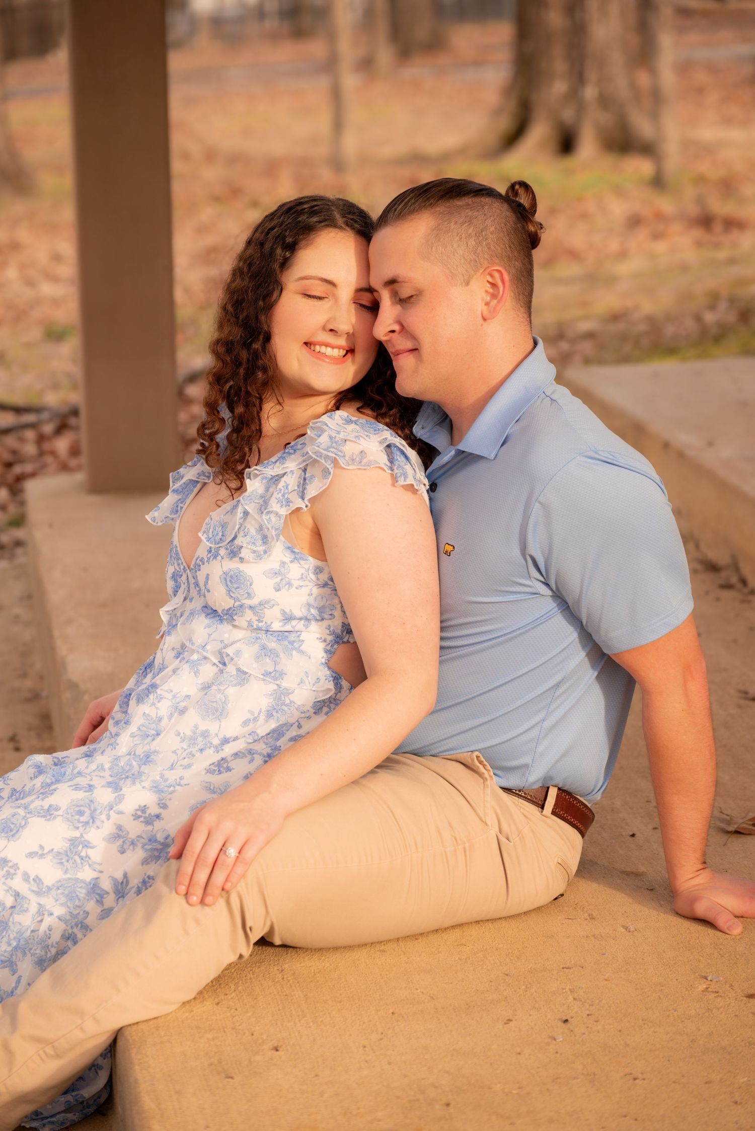 Couple sitting closely together on a stone surface, sharing a tender moment at sunset.