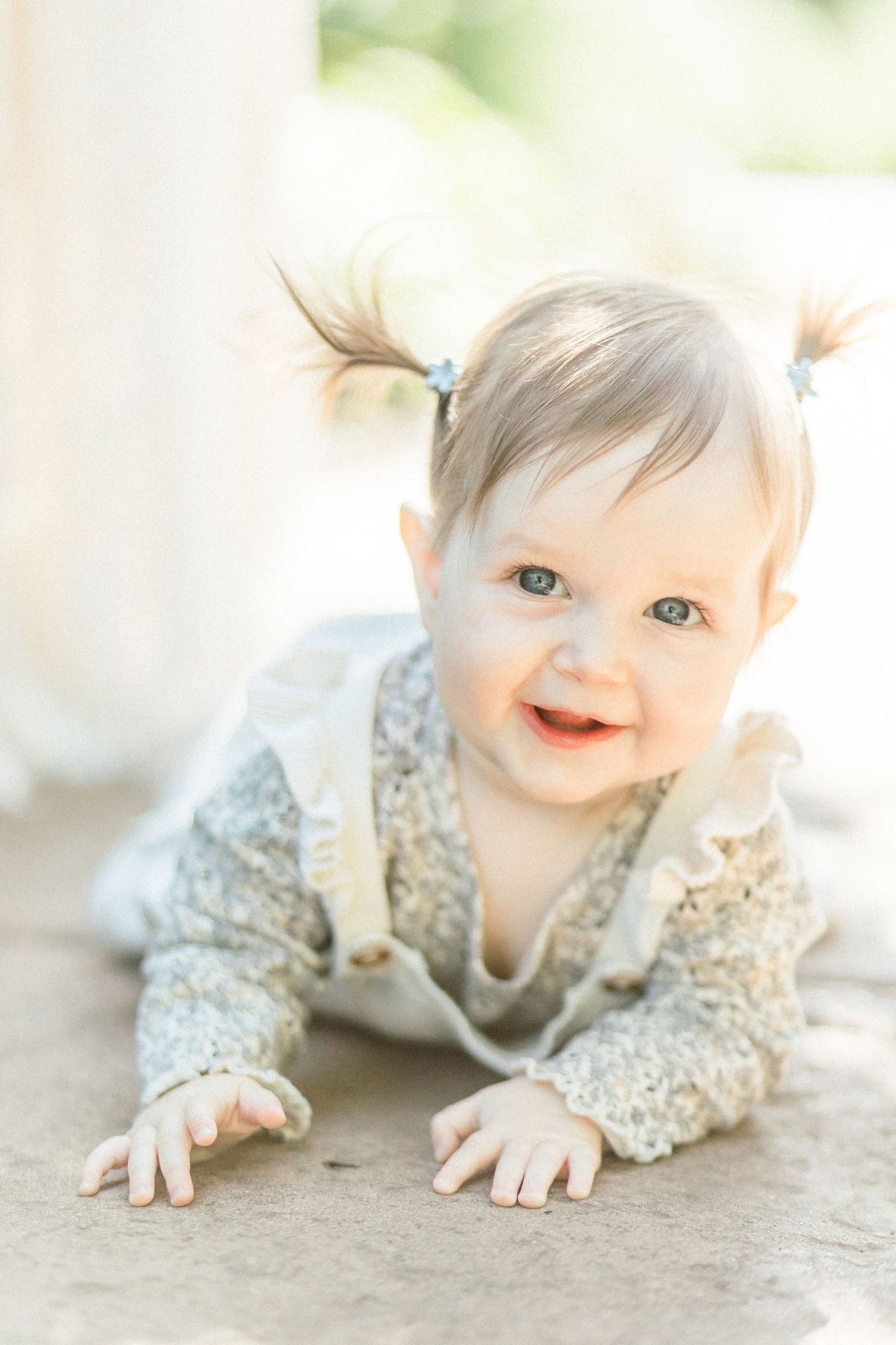 A baby wearing a lace dress crawls on the ground in a series of soft, dreamy photos taken in Springfield, Missouri.