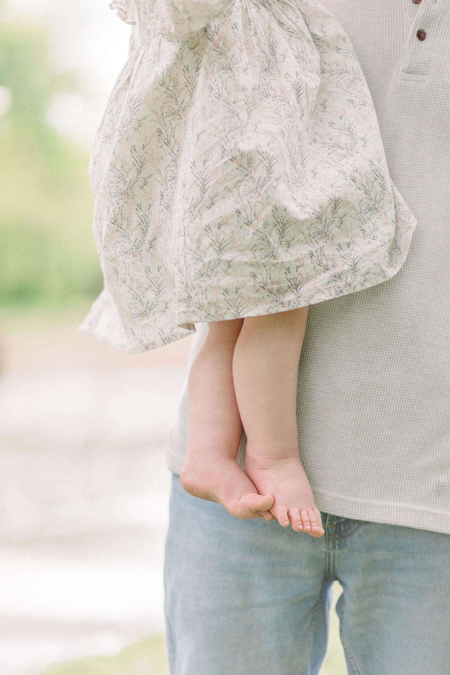 A close-up view of tiny bare feet against gray clothing in soft natural lighting in Springfield, Missouri.