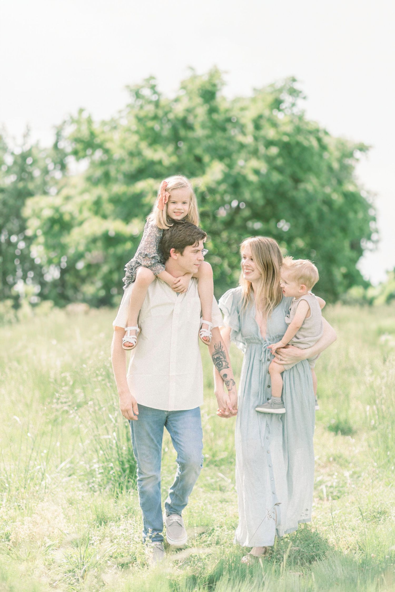Family spending time together in a sunlit meadow wearing soft pastel colors on a bright summer day in Springfield, Missouri.