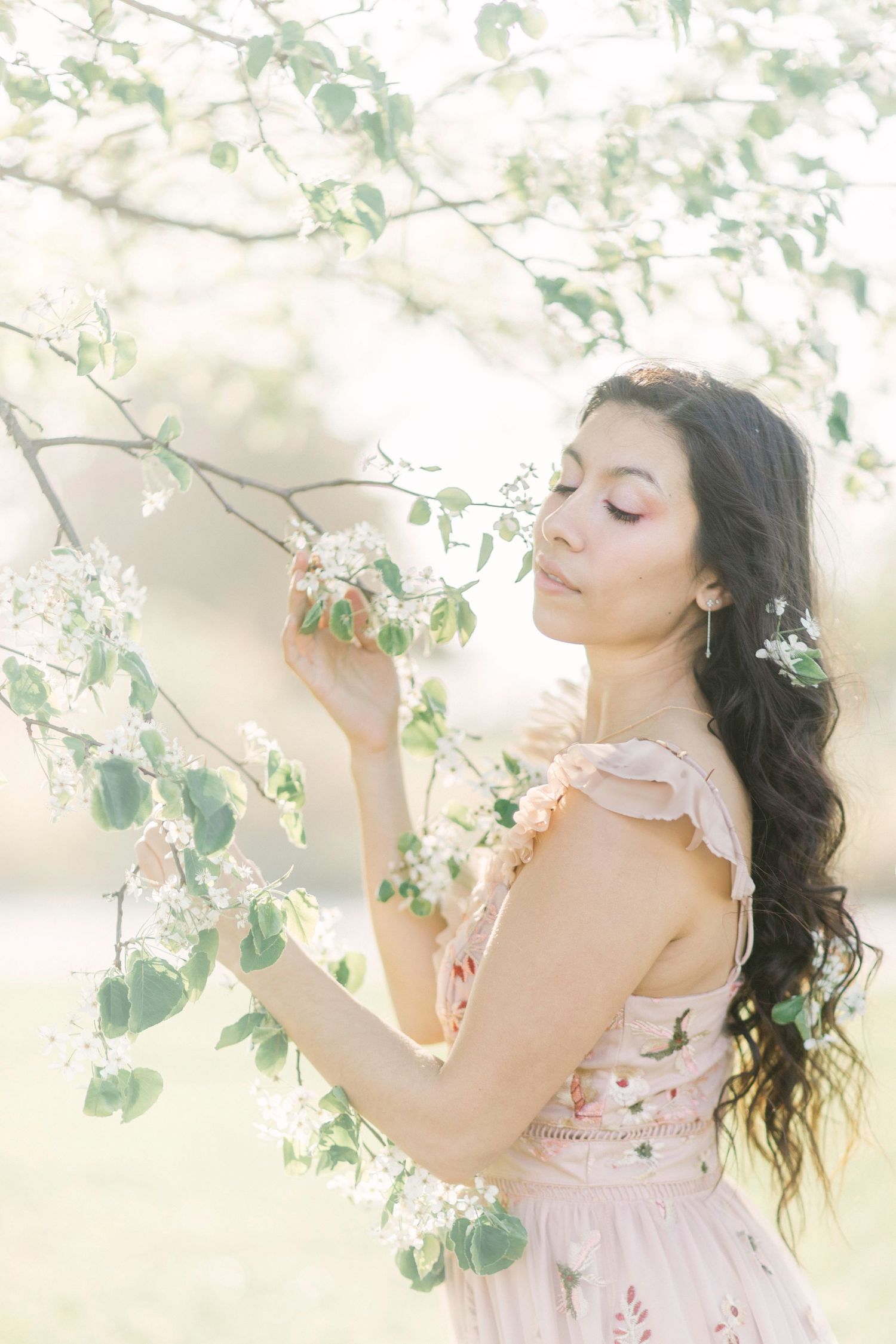 Ethereal spring portrait in soft light with flowering tree branches and pink dress creating a romantic atmosphere in Springfield, Missouri.