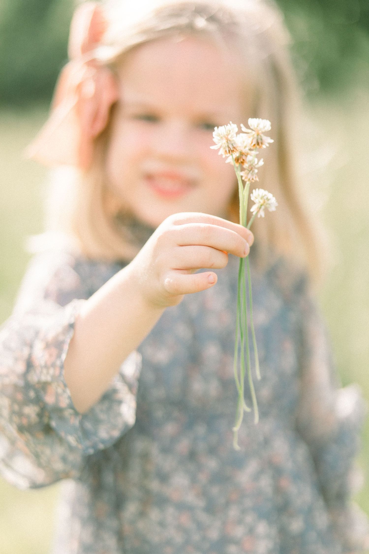 Delicate white wildflowers held in soft focus against a dreamy outdoor spring background with floral patterned dress in Springfield Missouri