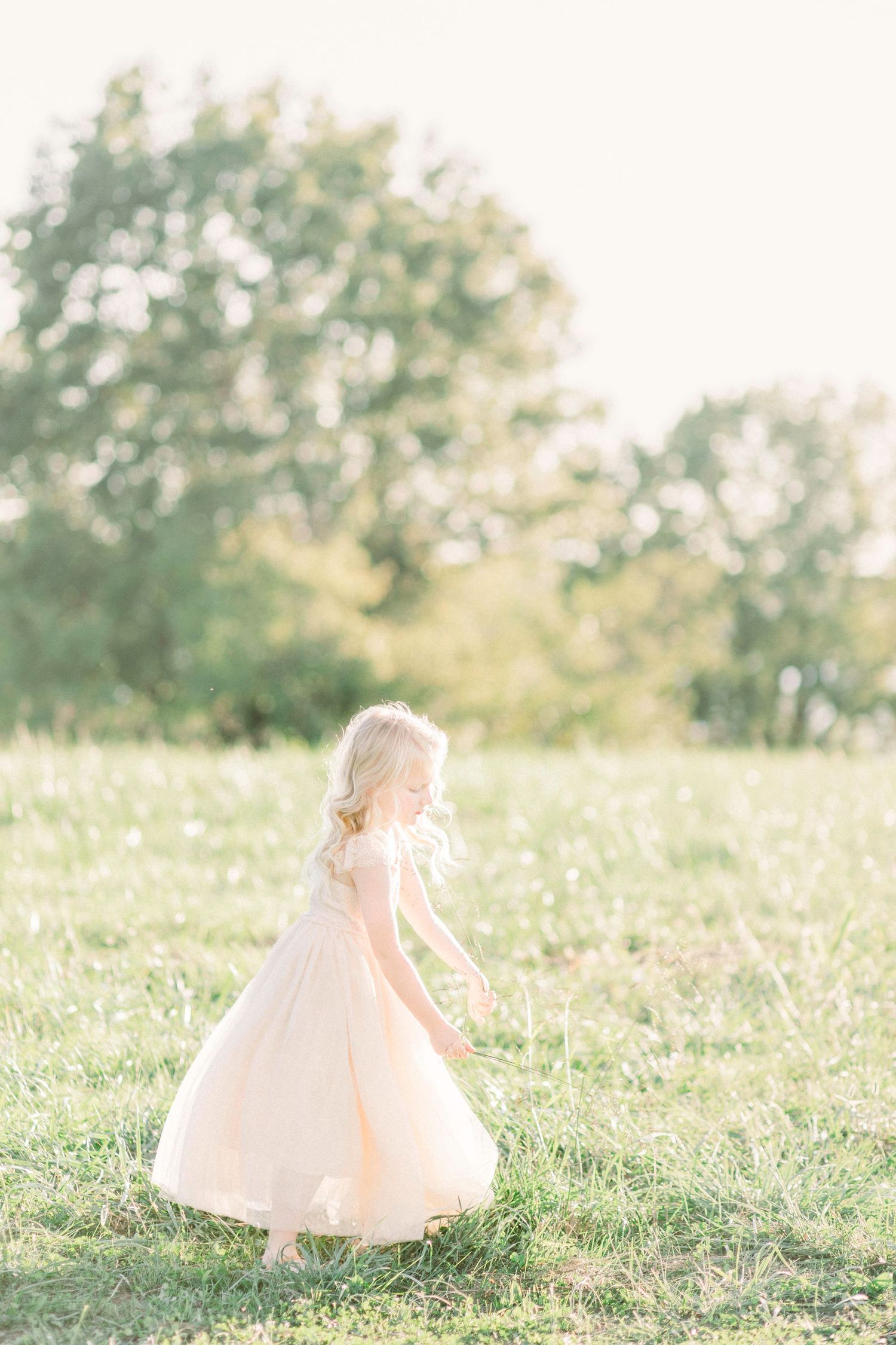 A child in a flowing tulle dress twirls gracefully in a sunlit  Springfield, Missouri meadow filled with delicate wildflowers.