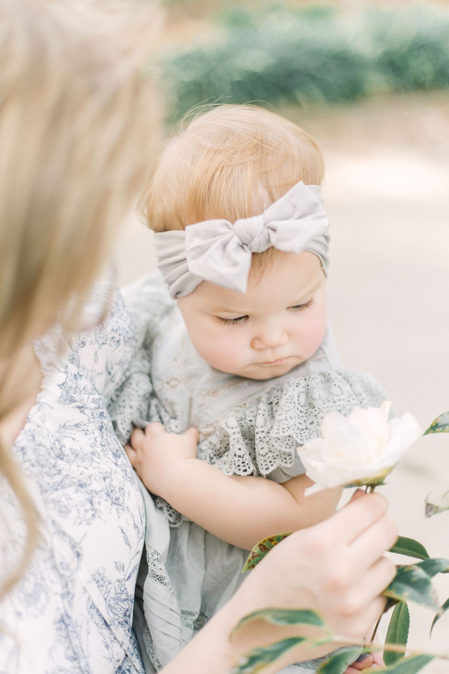Springfield, MO family photographer captures a tender moment of a mother and baby admiring a flower, embracing the beauty of motherhood.