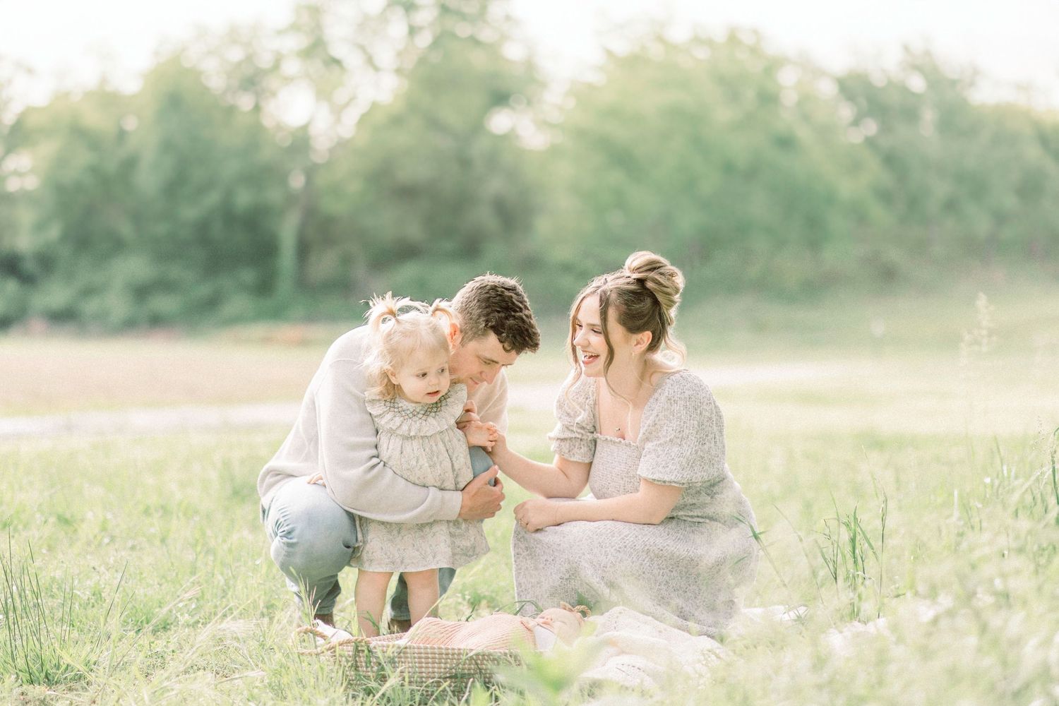Family enjoys tender moment together on grassy meadow during golden hour sunset in Springfield, Missouri.
