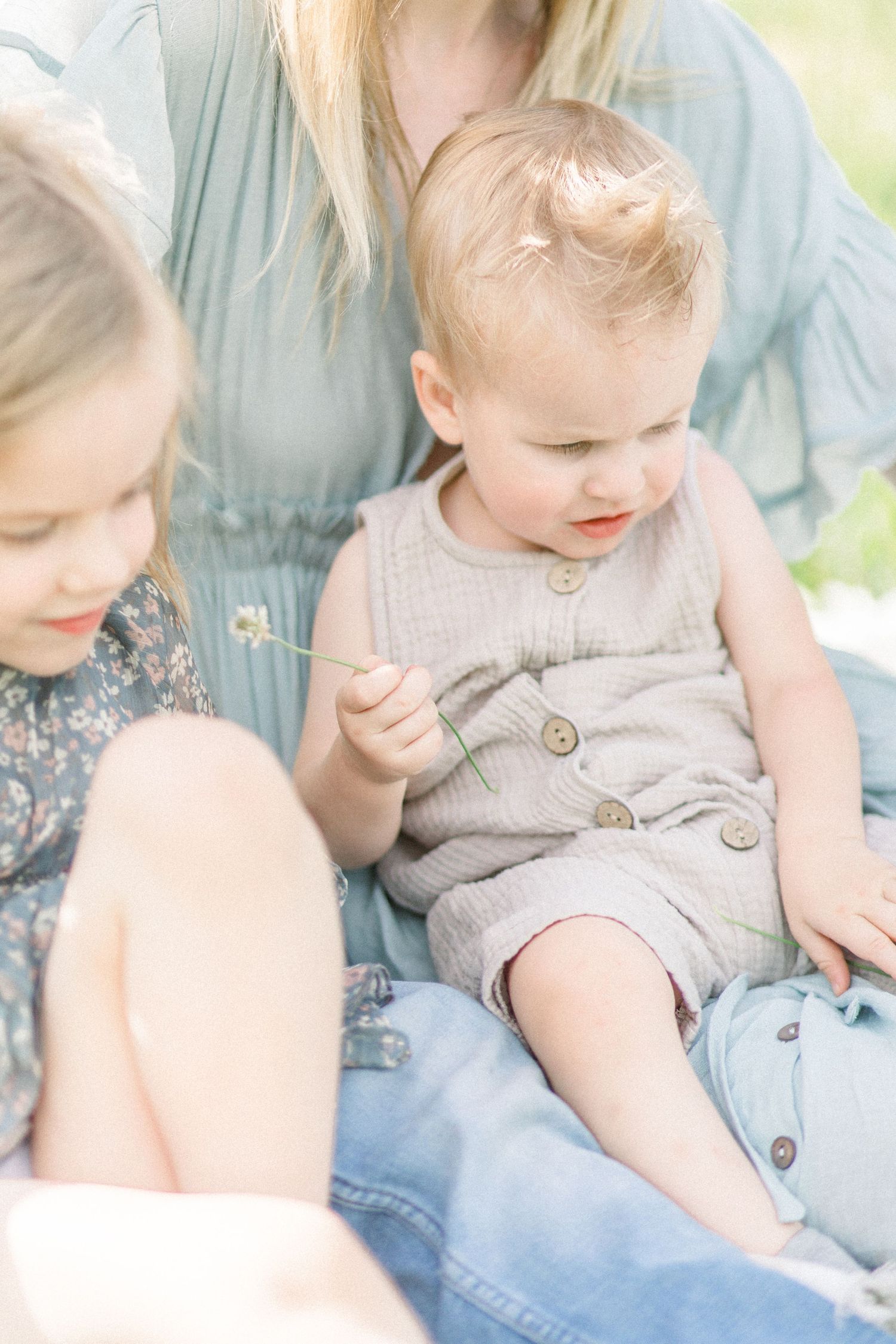 Children sit together on a sunny day wearing casual summer clothing in soft muted tones in Springfield, Missouri.
