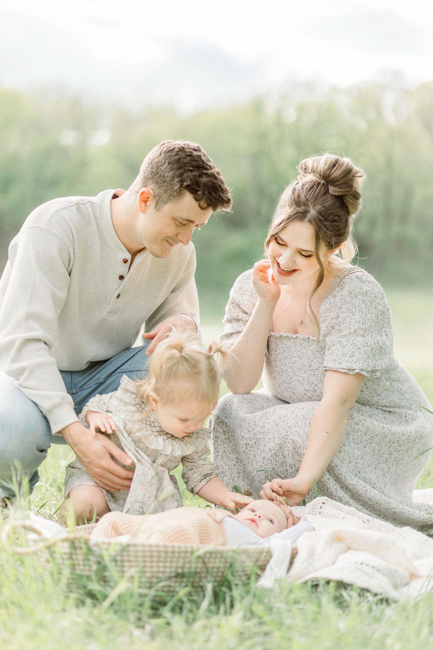 Family enjoying a picnic together on a sunny day in a grassy meadow, with a blanket and basket spread out in Springfield, Missouri.