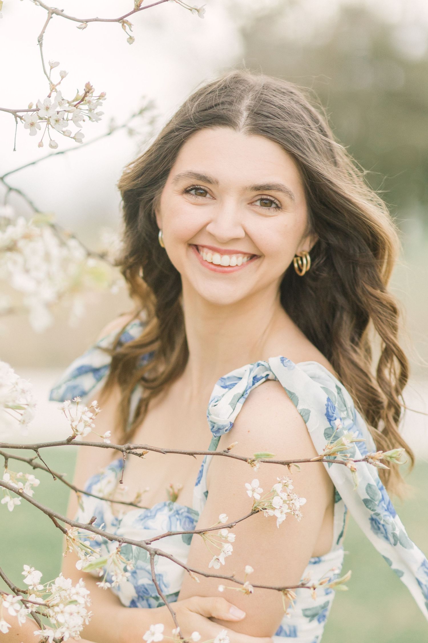 A springtime portrait featuring a woman in a blue floral dress surrounded by delicate white blossoms in Springfield, Missouri.