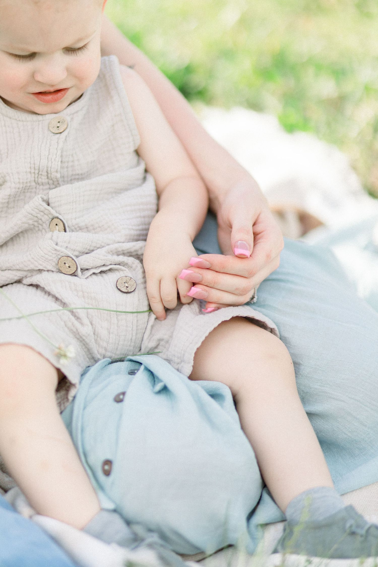 Close-up of toddler in beige buttoned romper sitting on light blue fabric in Springfield, Missouri.
