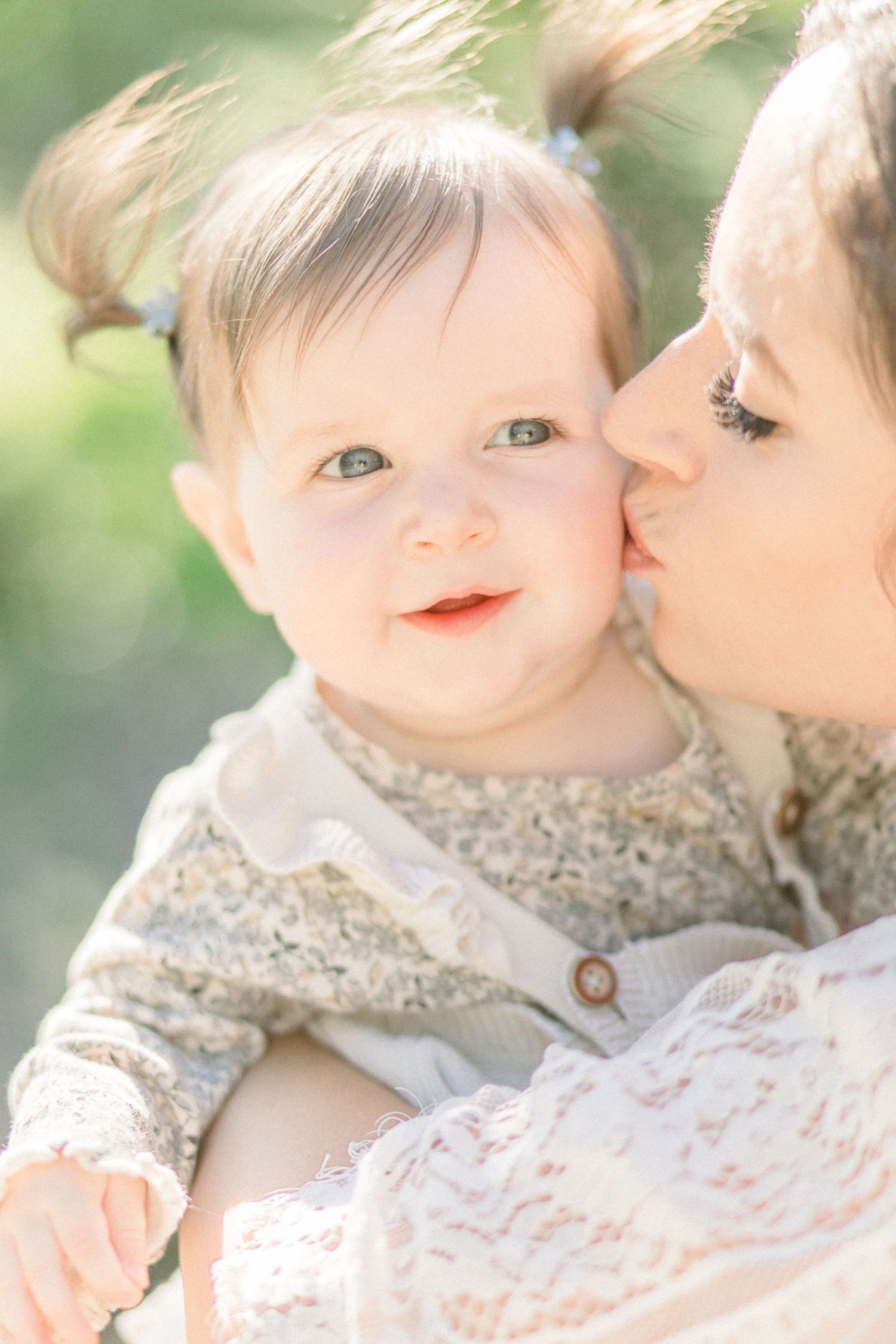 A tender moment captured between parent and baby in soft natural light wearing floral and lace clothing in Springfield, Missouri.