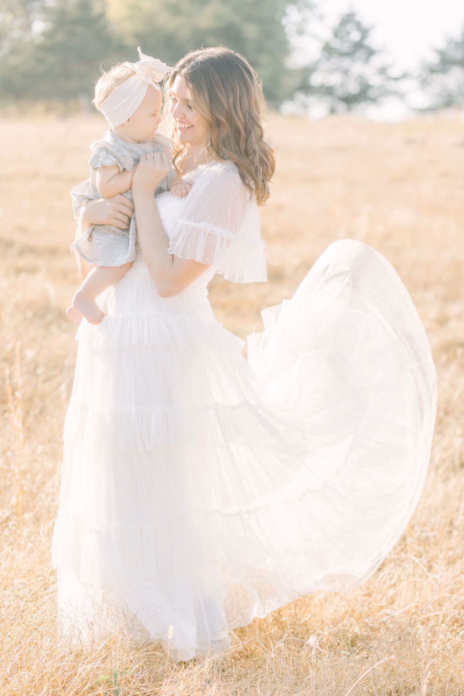 Flowing white dress catches breeze in sun-drenched summer field in Springfield, MO.