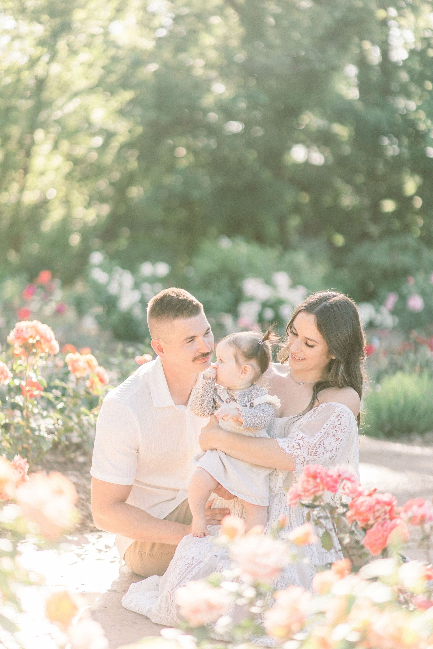 A family shares joyful moments together in a garden with blooming coral-colored flowers on a sunny afternoon in Springfield, Missouri.