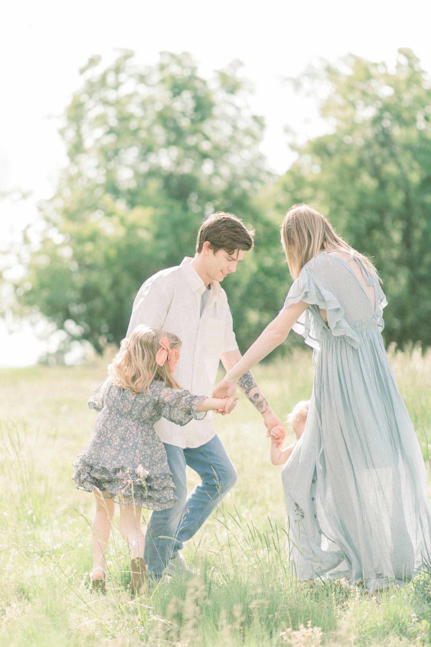 A family in light blue and denim enjoy a romantic moment together in a sunlit Springfield, Missouri field.