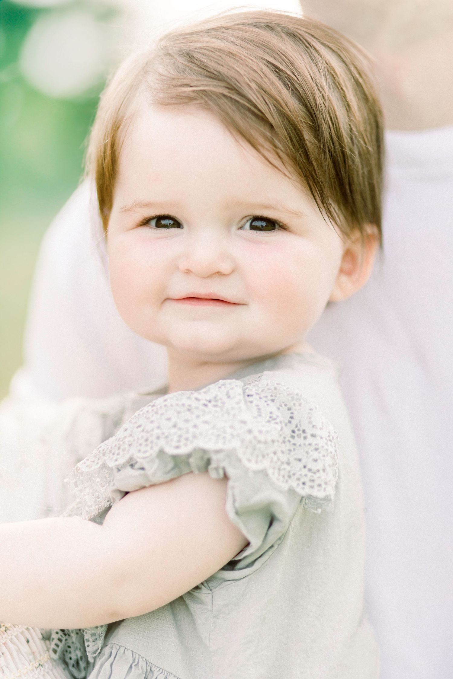 Close up portrait of baby wearing white lace collar against soft green background in Marshfield, MO.
