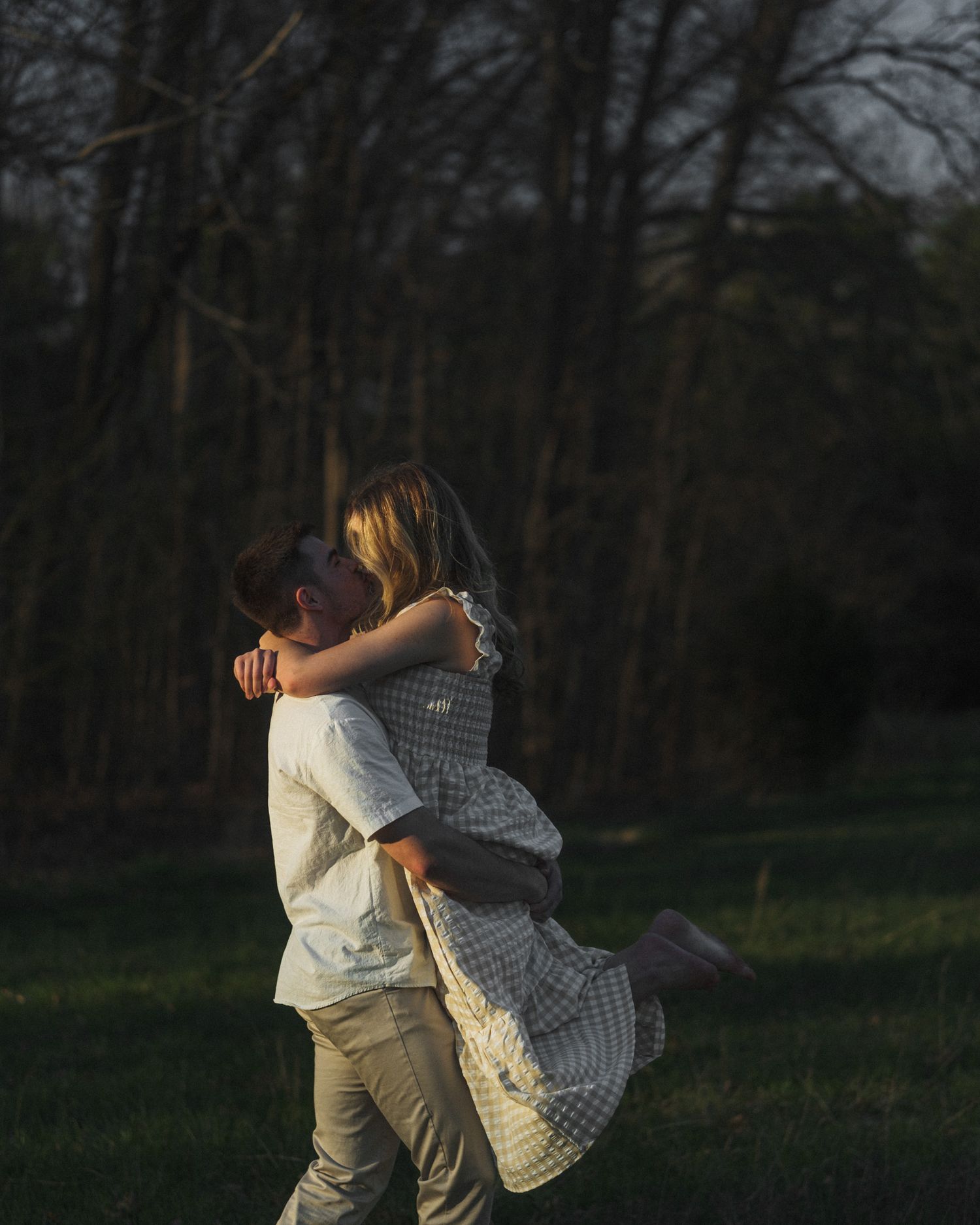 Romantic couple embracing and spinning in a field at sunset.