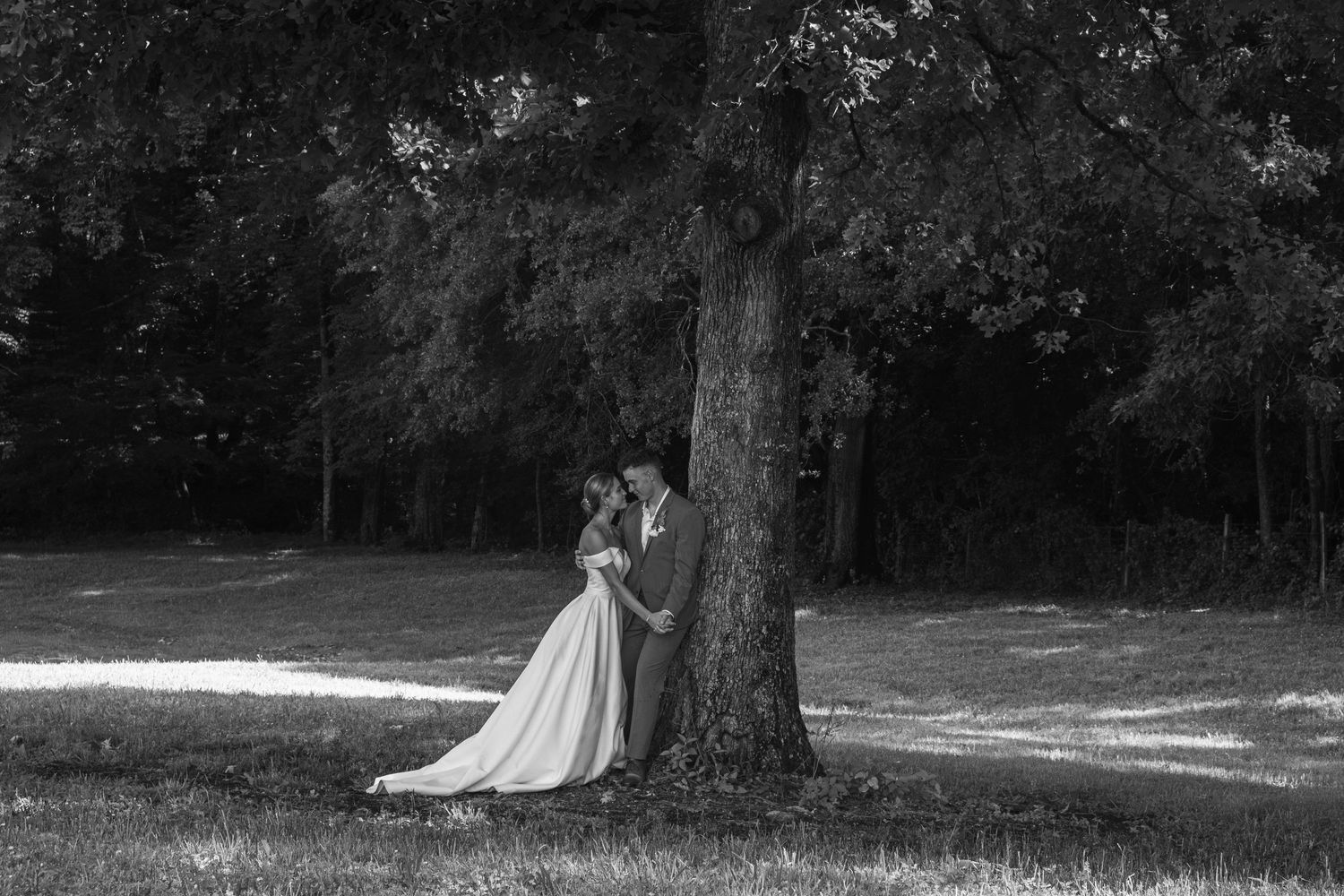 Artistic black and white wedding portraits in a natural outdoor setting.