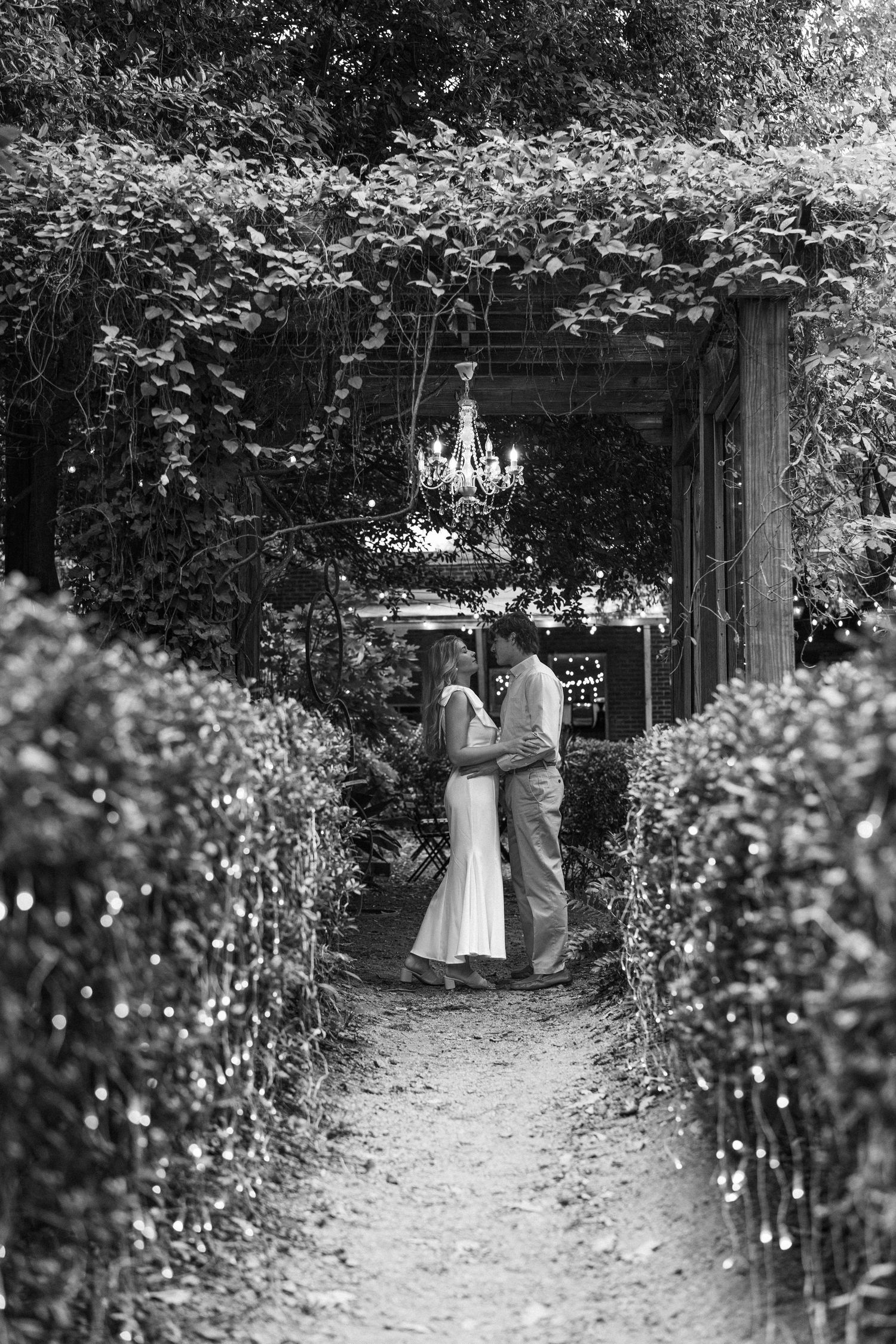 A garden path with hanging chandeliers and green foliage creating a magical setting.