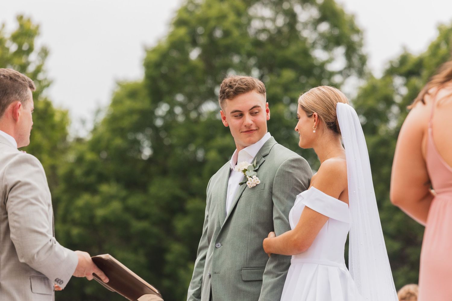 Candid moment during outdoor wedding ceremony with couple and officiant.