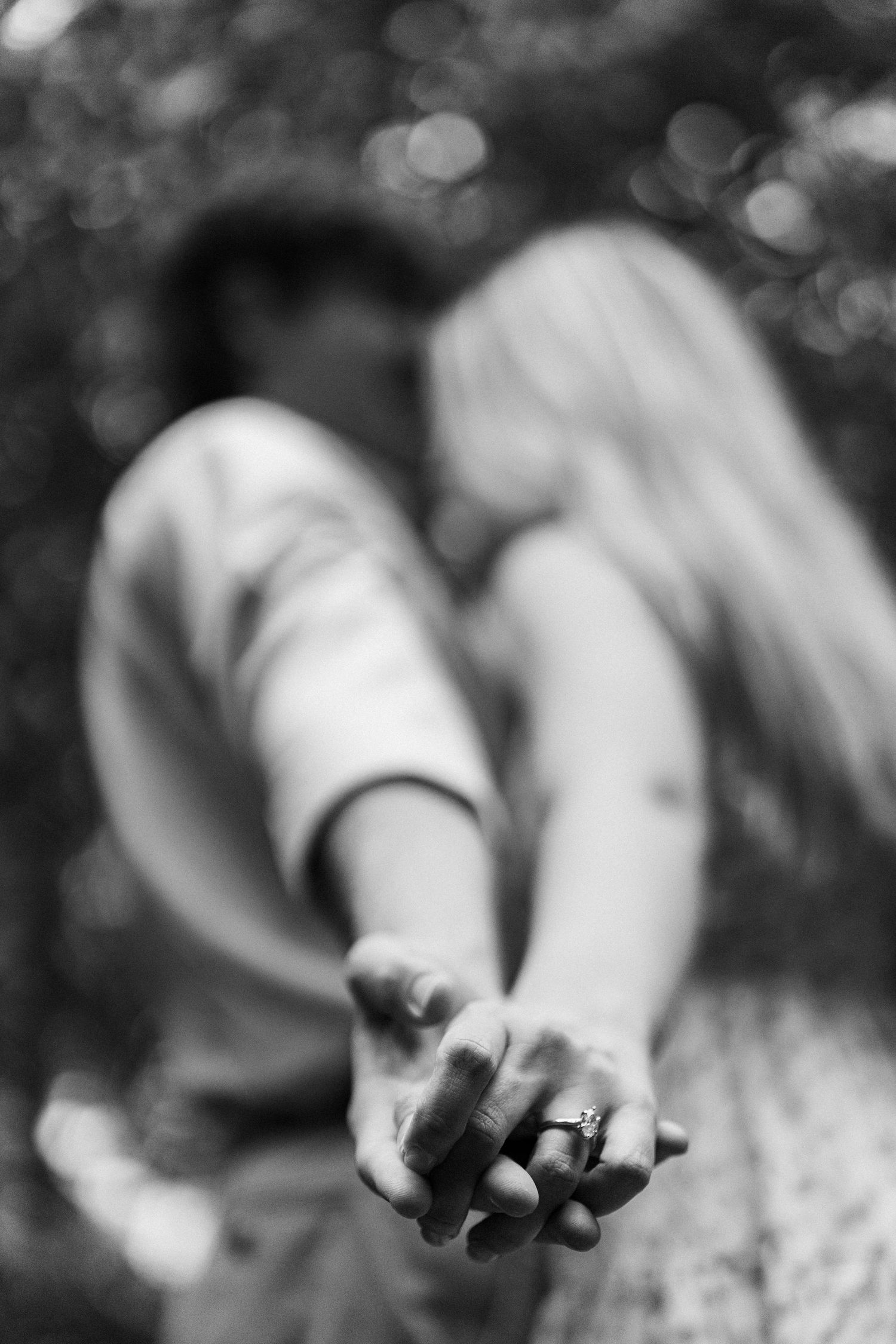 Close-up black and white photo of two hands clasped together, showing a wedding ring.