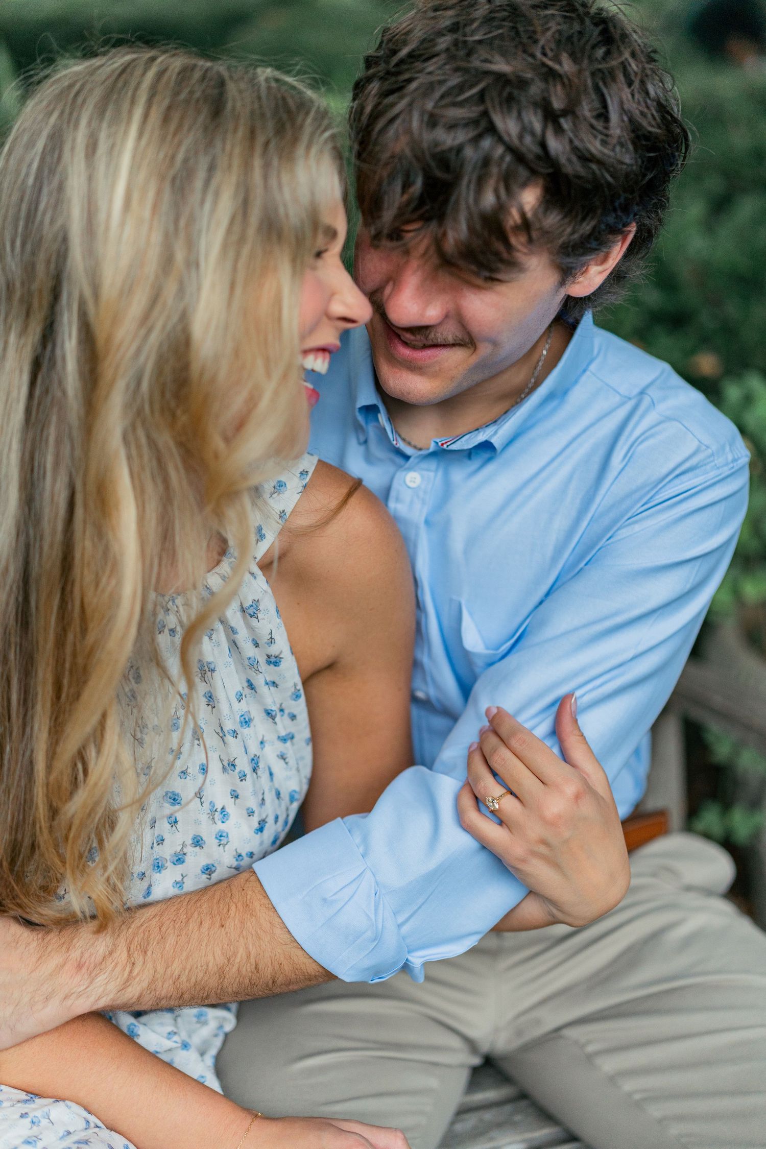 Romantic couple in blue shirt and floral dress share intimate moments in an outdoor setting.