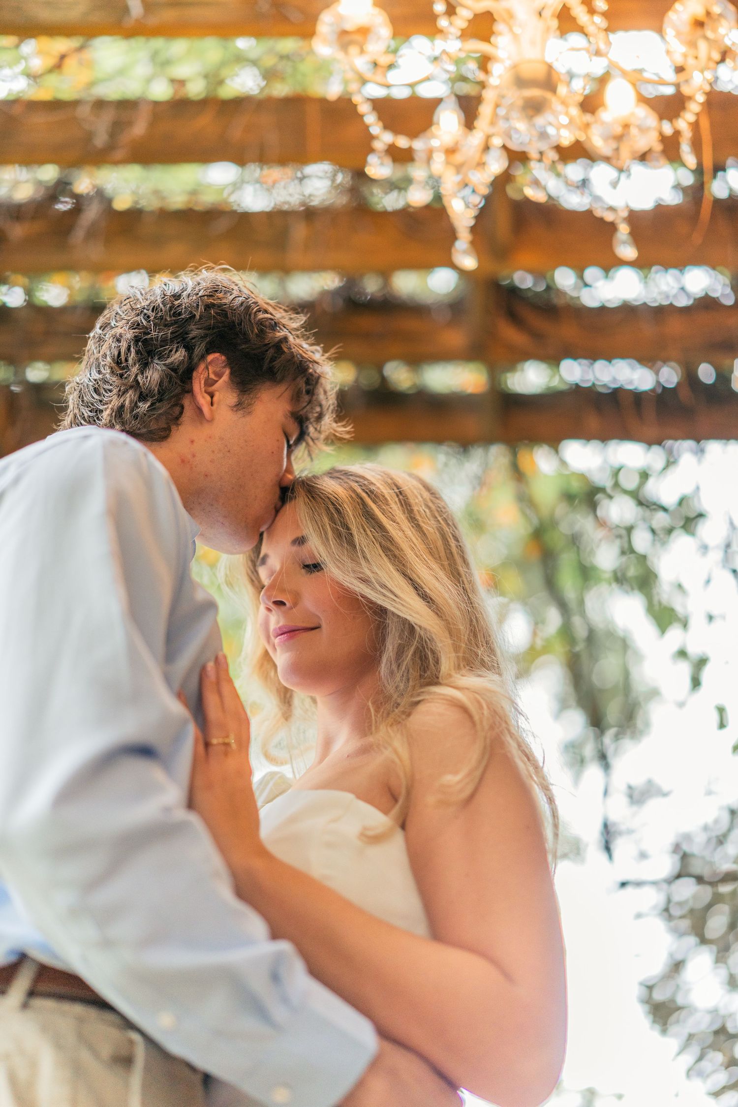 A tender moment shared under a pergola with twinkling lights overhead.